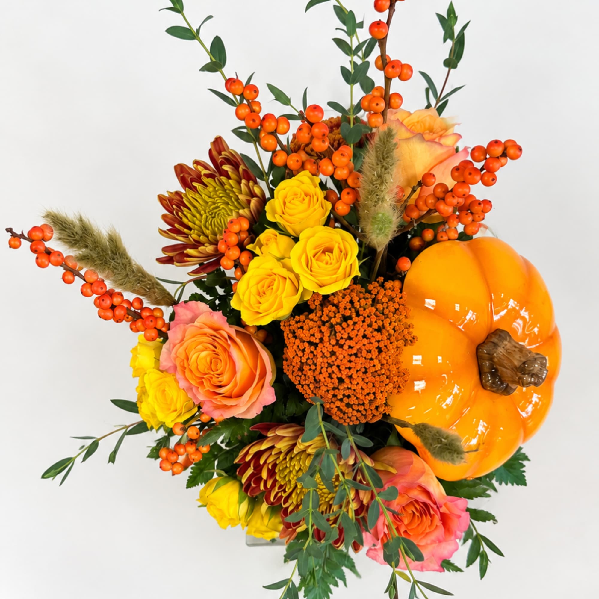 Autumn bouquet with yellow and peach roses, mums, berries, and a pumpkin accent