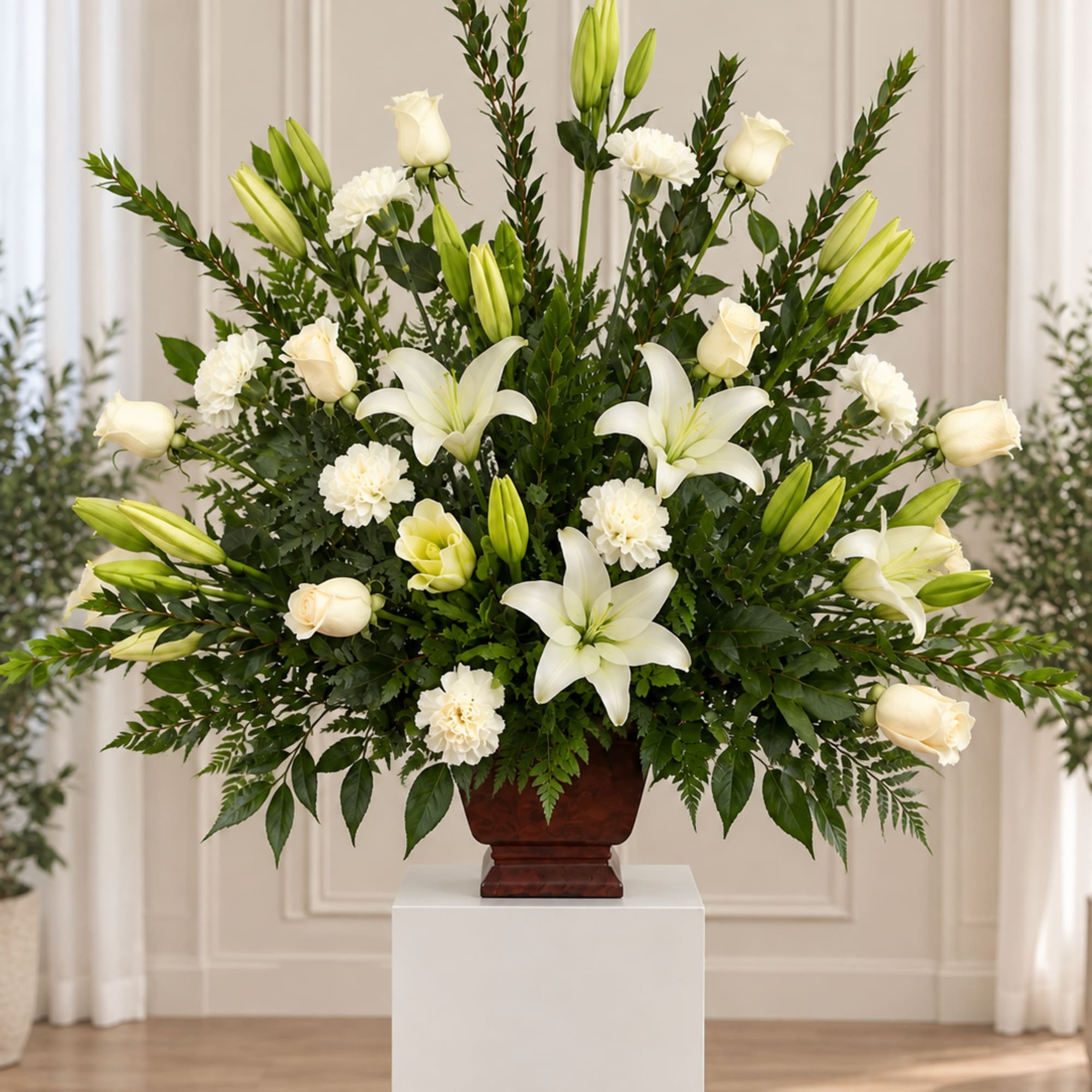 White lilies and roses arranged in a dark vase on a pedestal
