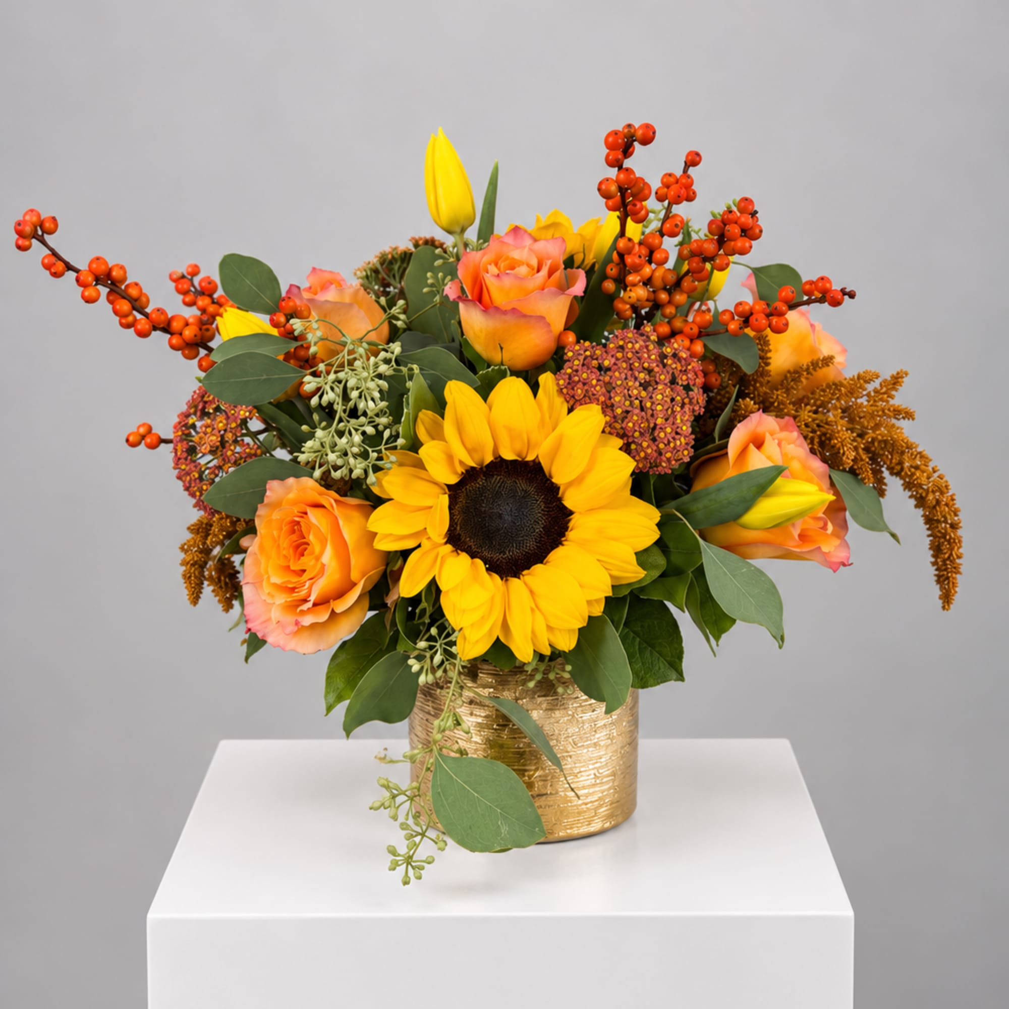 Sunflower and peach rose arrangement in a gold vase