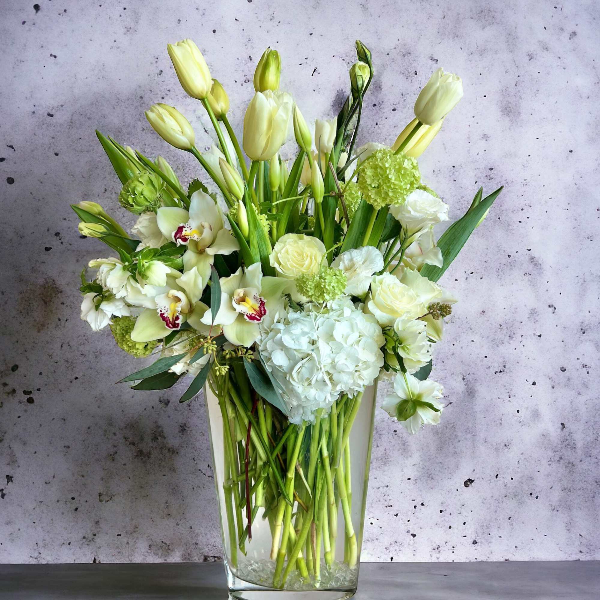 White and pale green floral arrangement in a clear glass vase