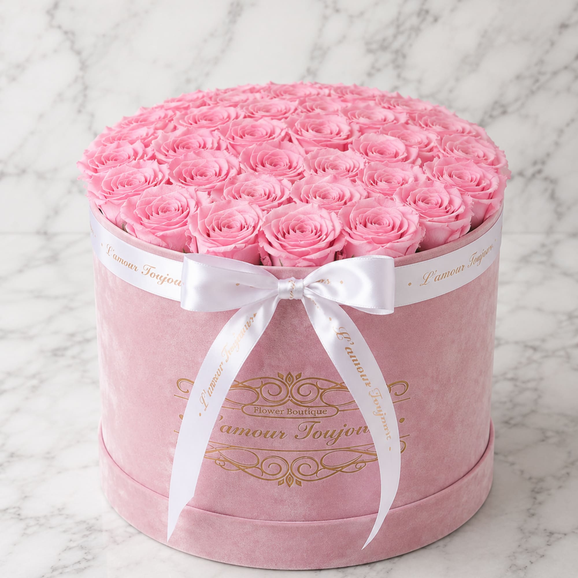 Round pink box filled with pink roses and tied with a white ribbon