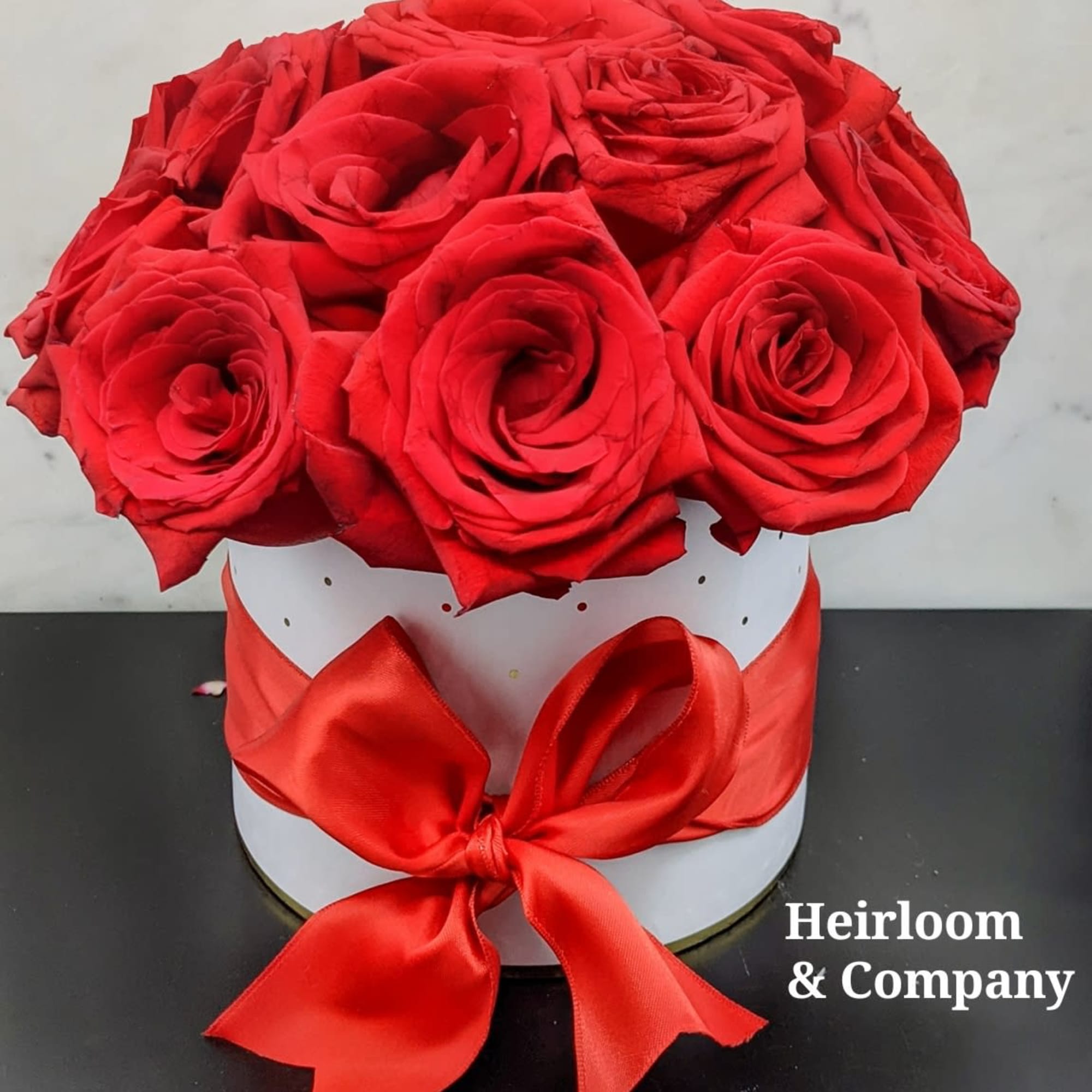Red roses arranged in a white round box with a red ribbon bow, photo 2 of 2