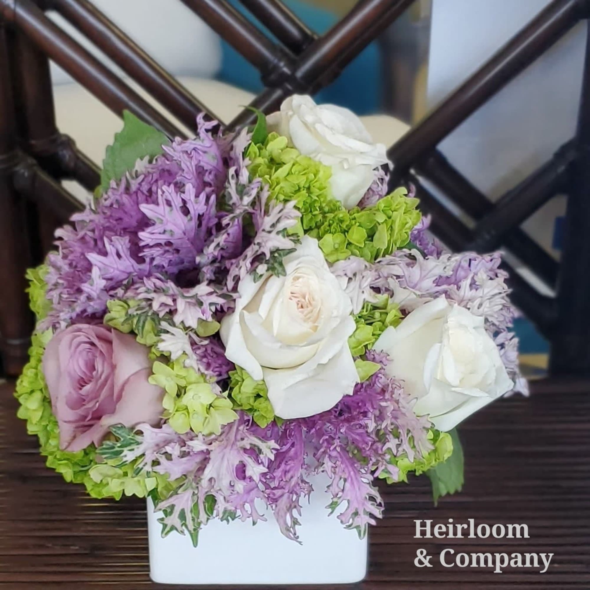 Bouquet of white and lavender roses with green hydrangeas in a white container