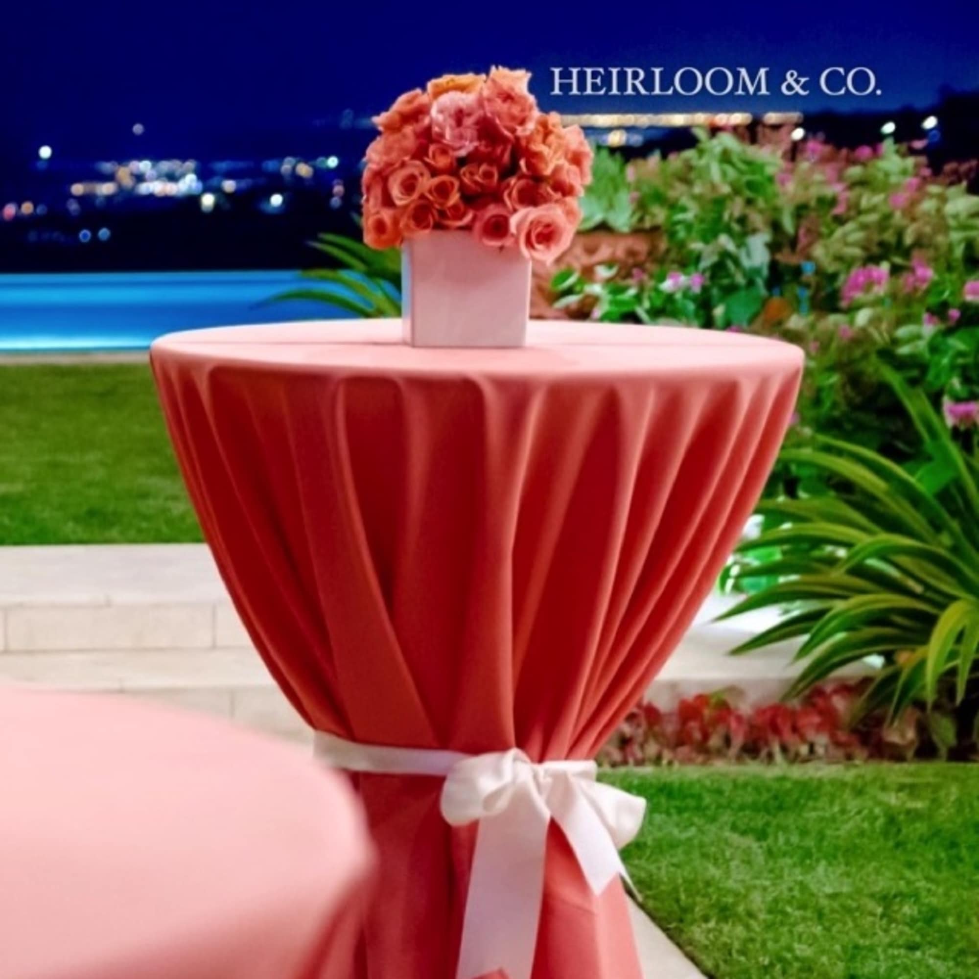 Pink rose bouquet on a tall draped table with a white ribbon