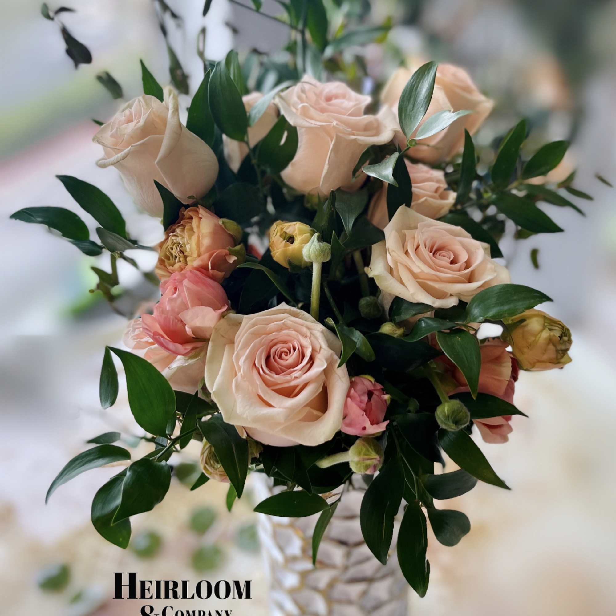 Peach and pink roses arranged in a white textured vase