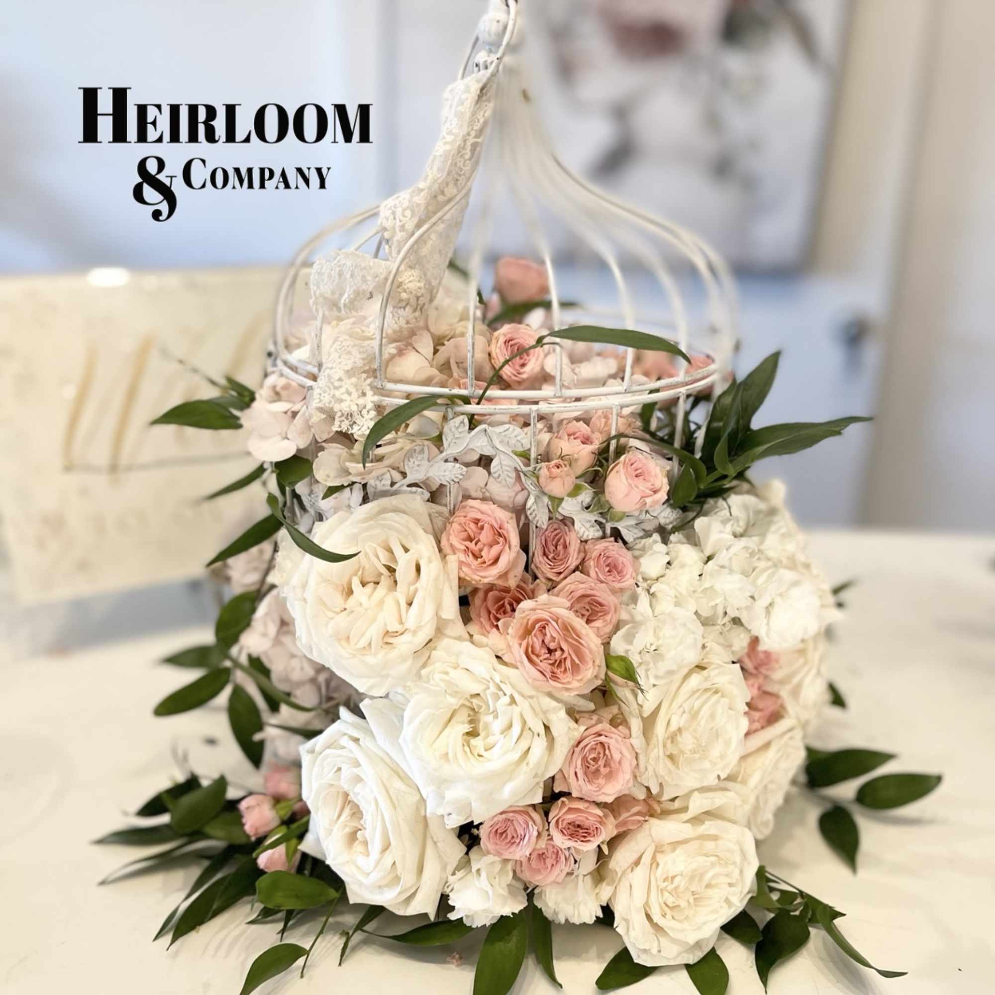 Pink and white roses arranged in a white birdcage