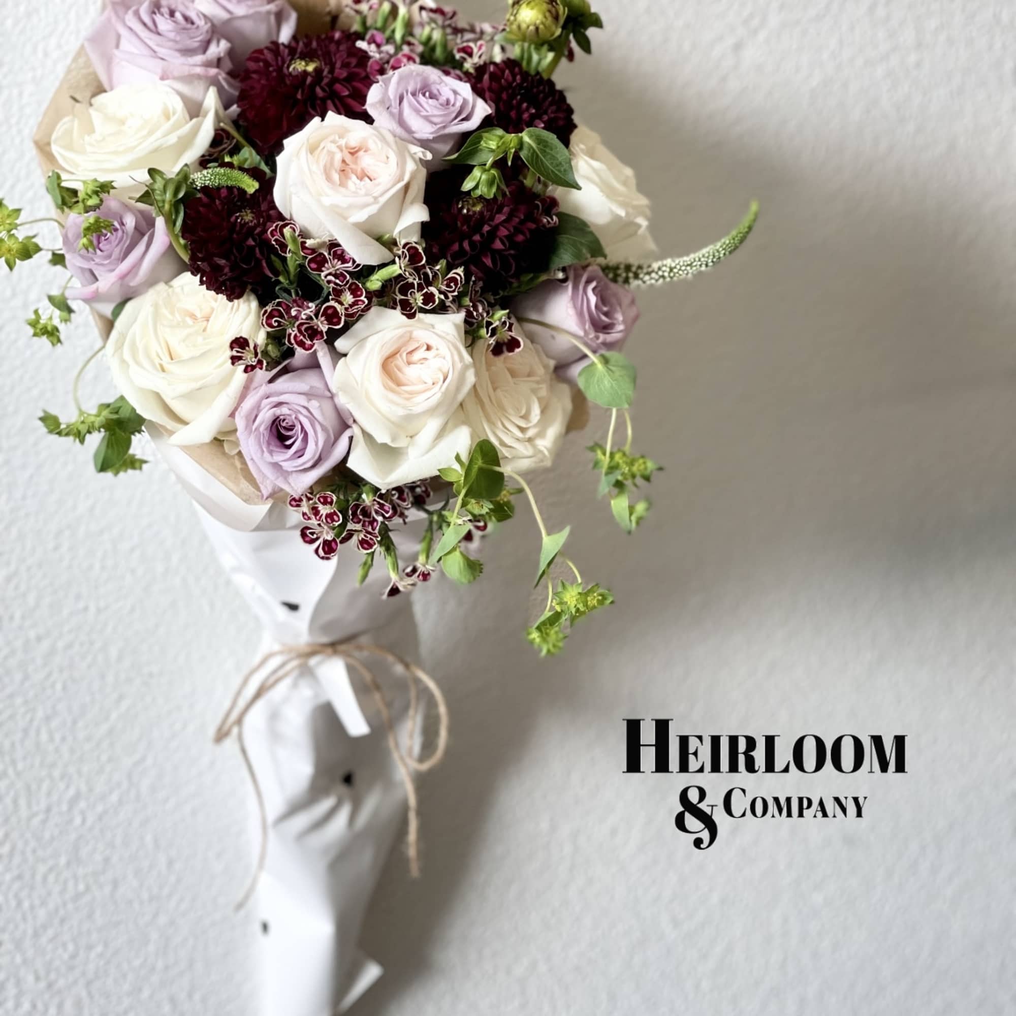 Bouquet of white, blush, and lavender roses with dark burgundy blooms