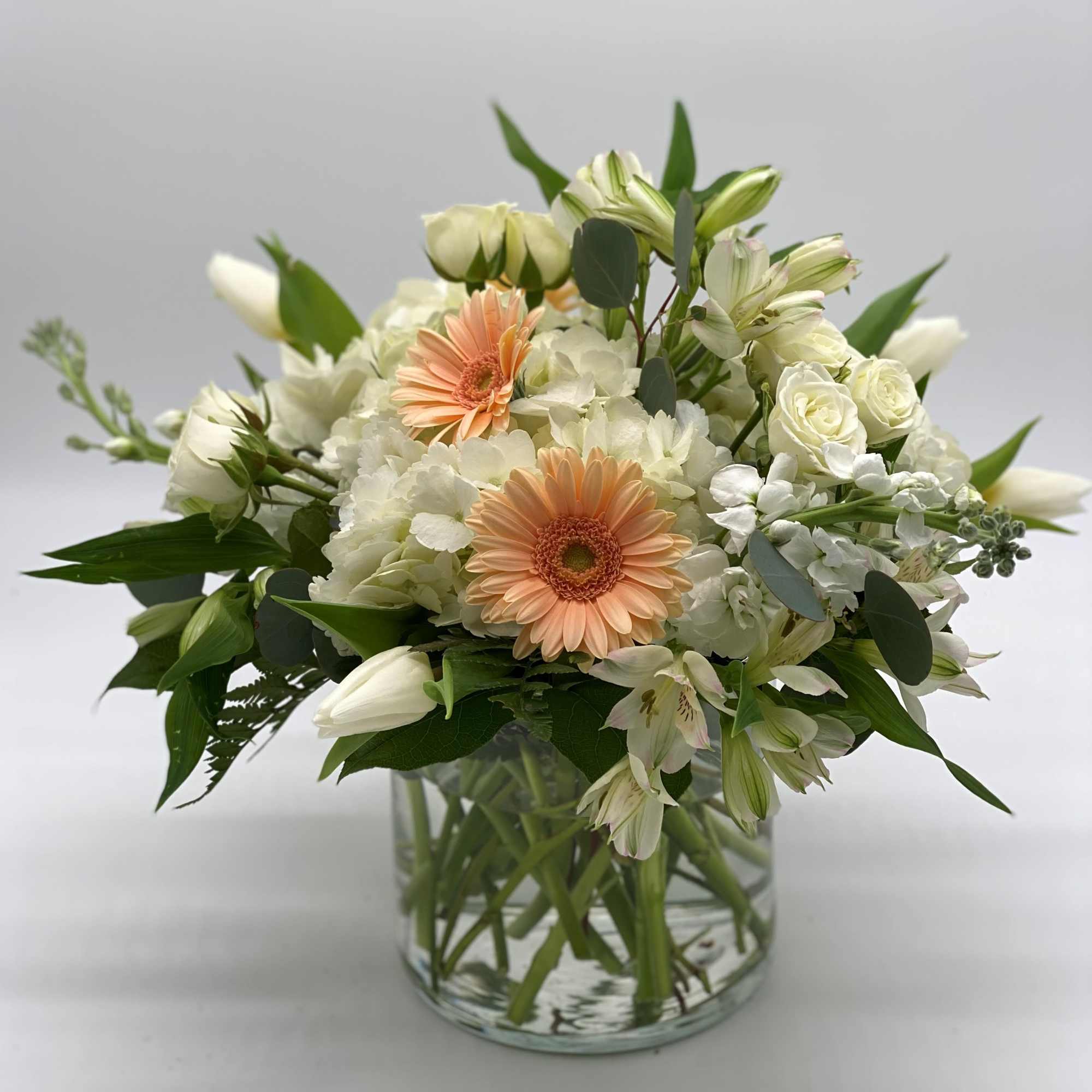 White and peach mixed bouquet in a clear glass vase