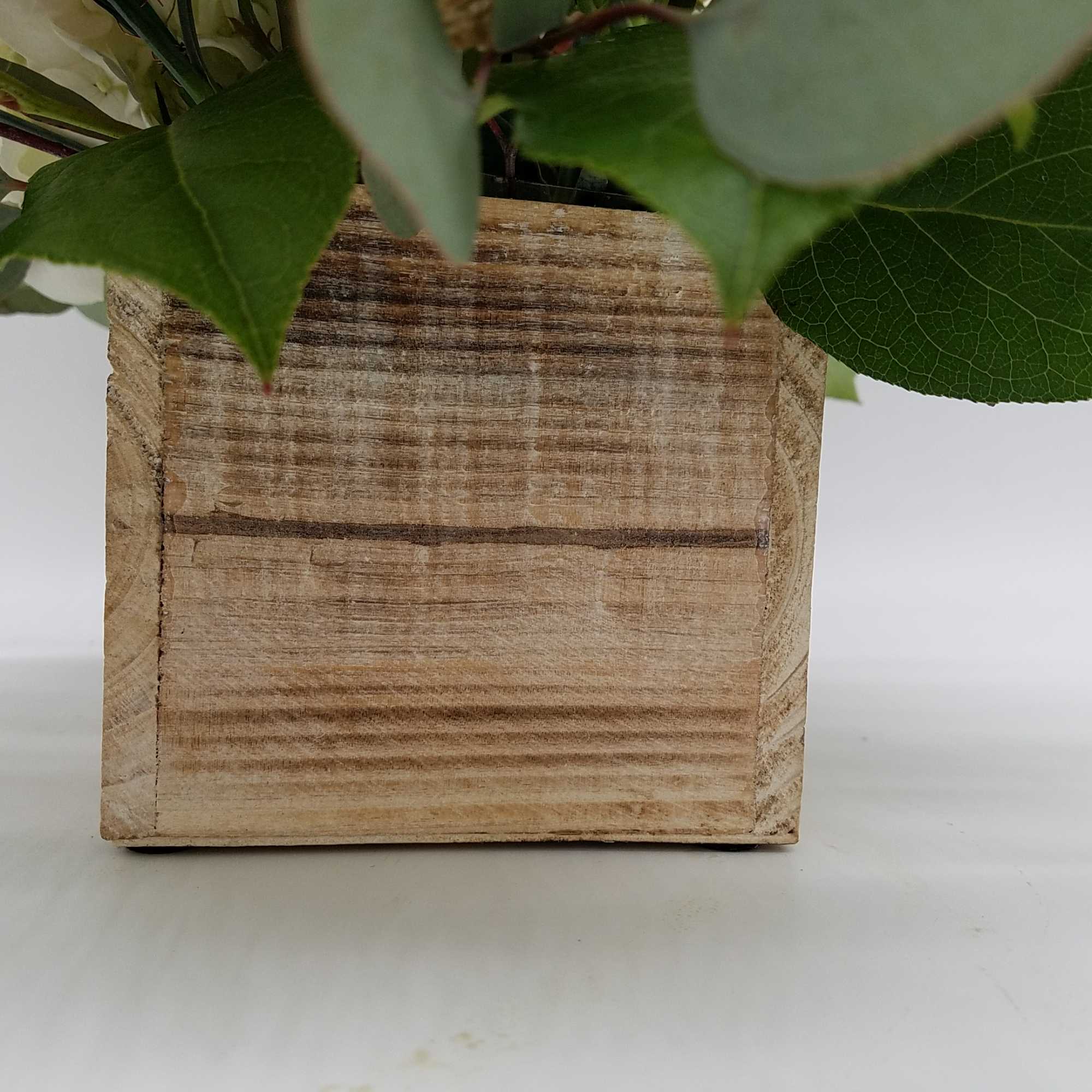 Wooden planter with leafy greenery against a white background