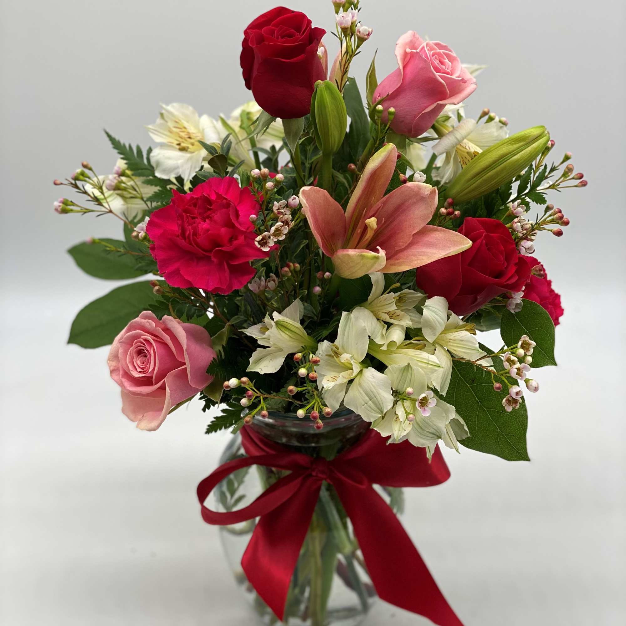 Mixed bouquet of roses, lilies, and carnations in a glass vase with a red ribbon, photo 3 of 3