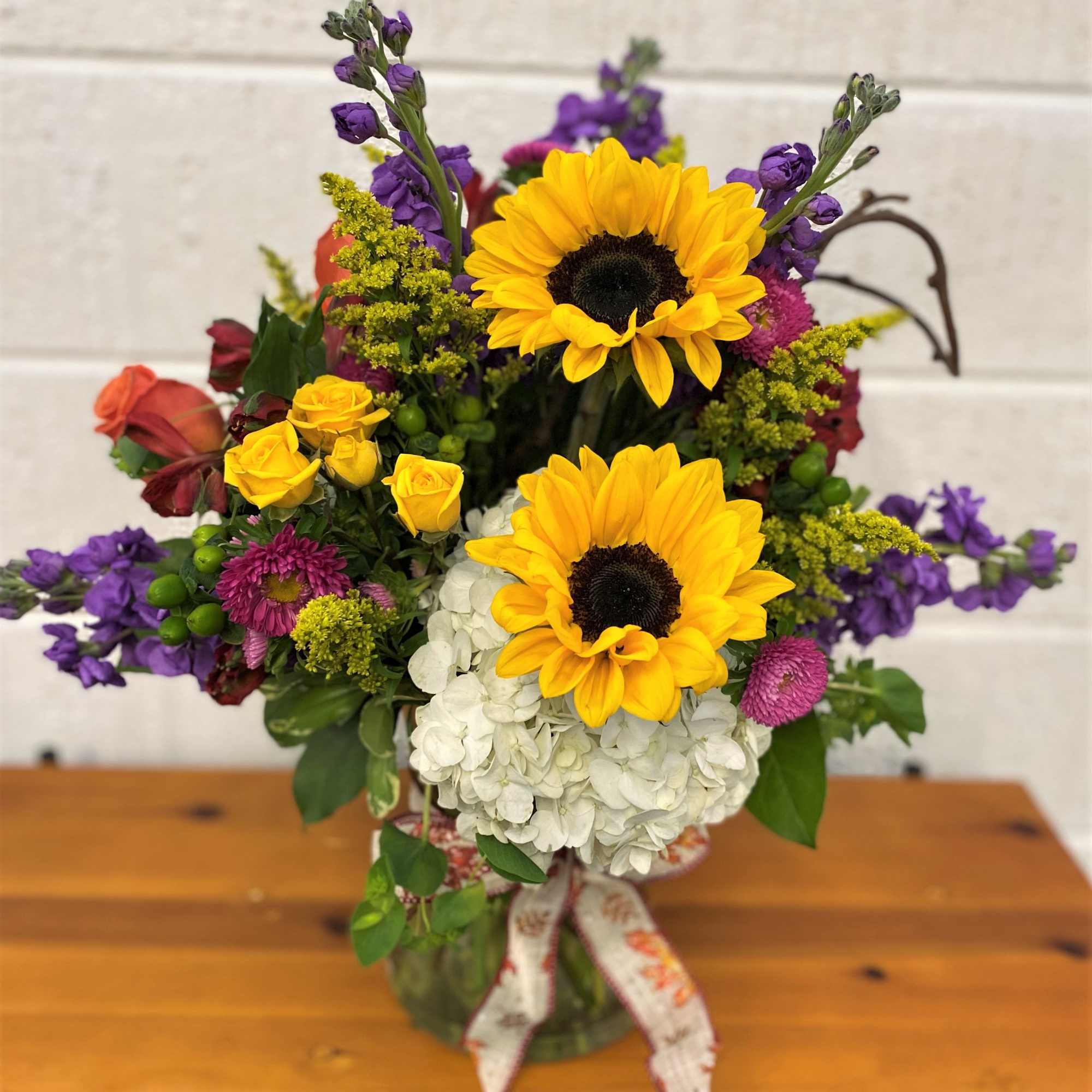 Mix of Fresh Blooms designed in a large gathering vase accented with