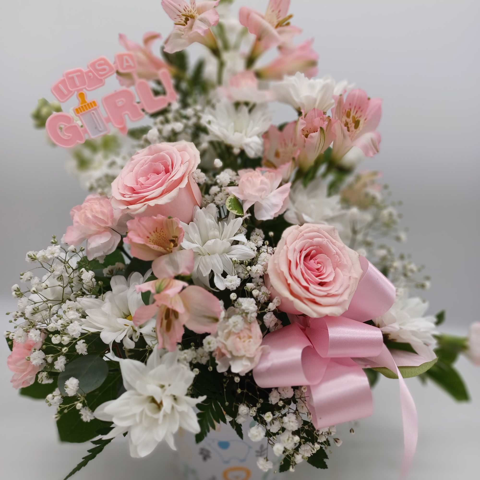 Pink and white bouquet in a vase with a pink ribbon and "It's a Girl" topper