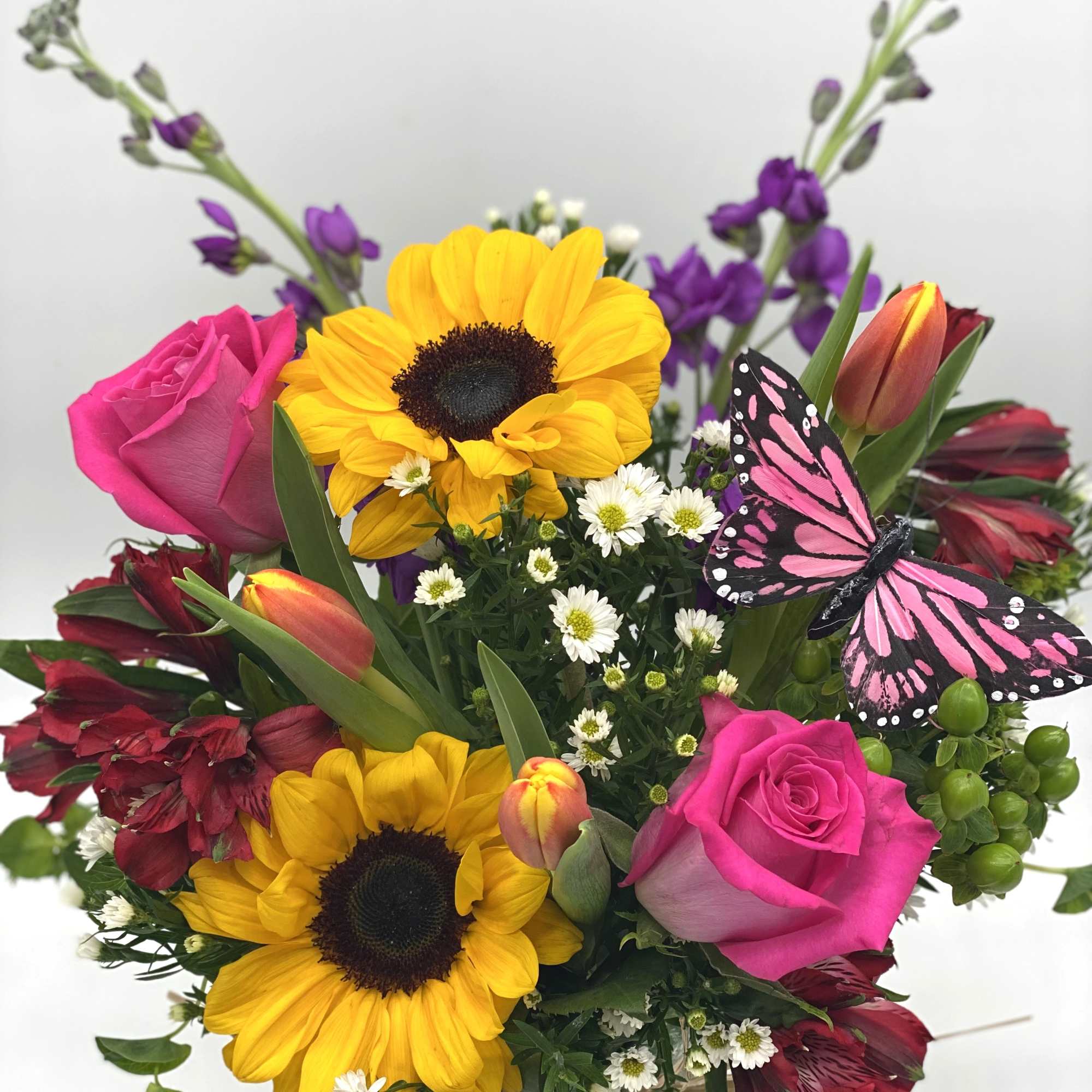 Bouquet of sunflowers, pink roses, and tulips with a butterfly decoration