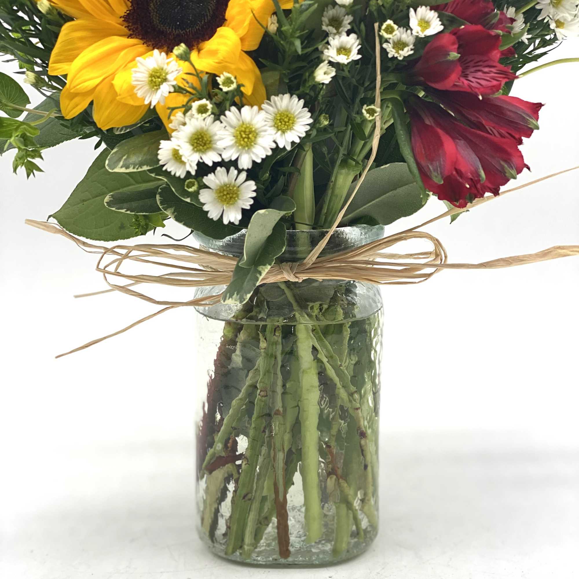 Bouquet of yellow sunflowers and red alstroemeria in a glass vase
