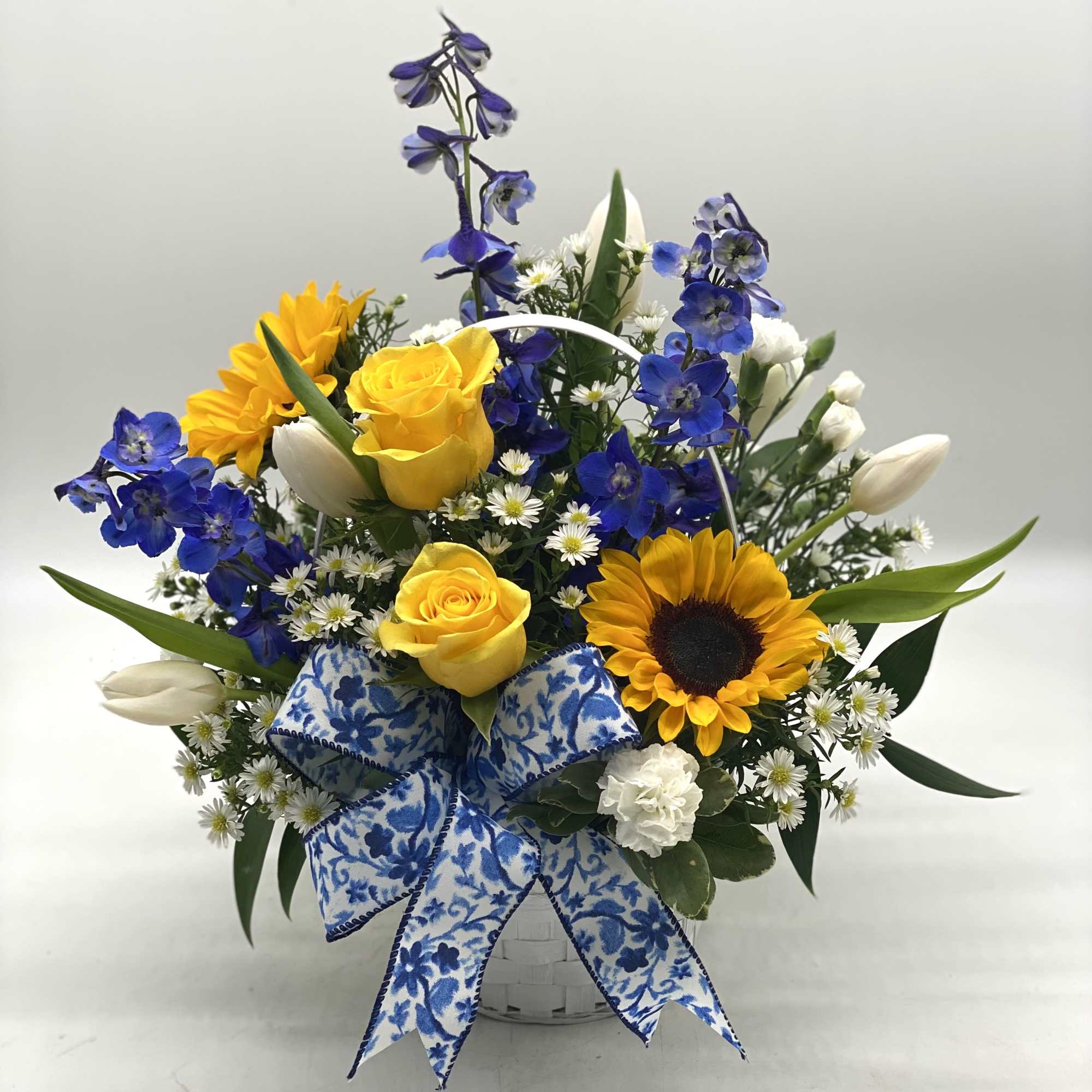 Basket arrangement with yellow roses, sunflowers, blue flowers, and white tulips, photo 3 of 5