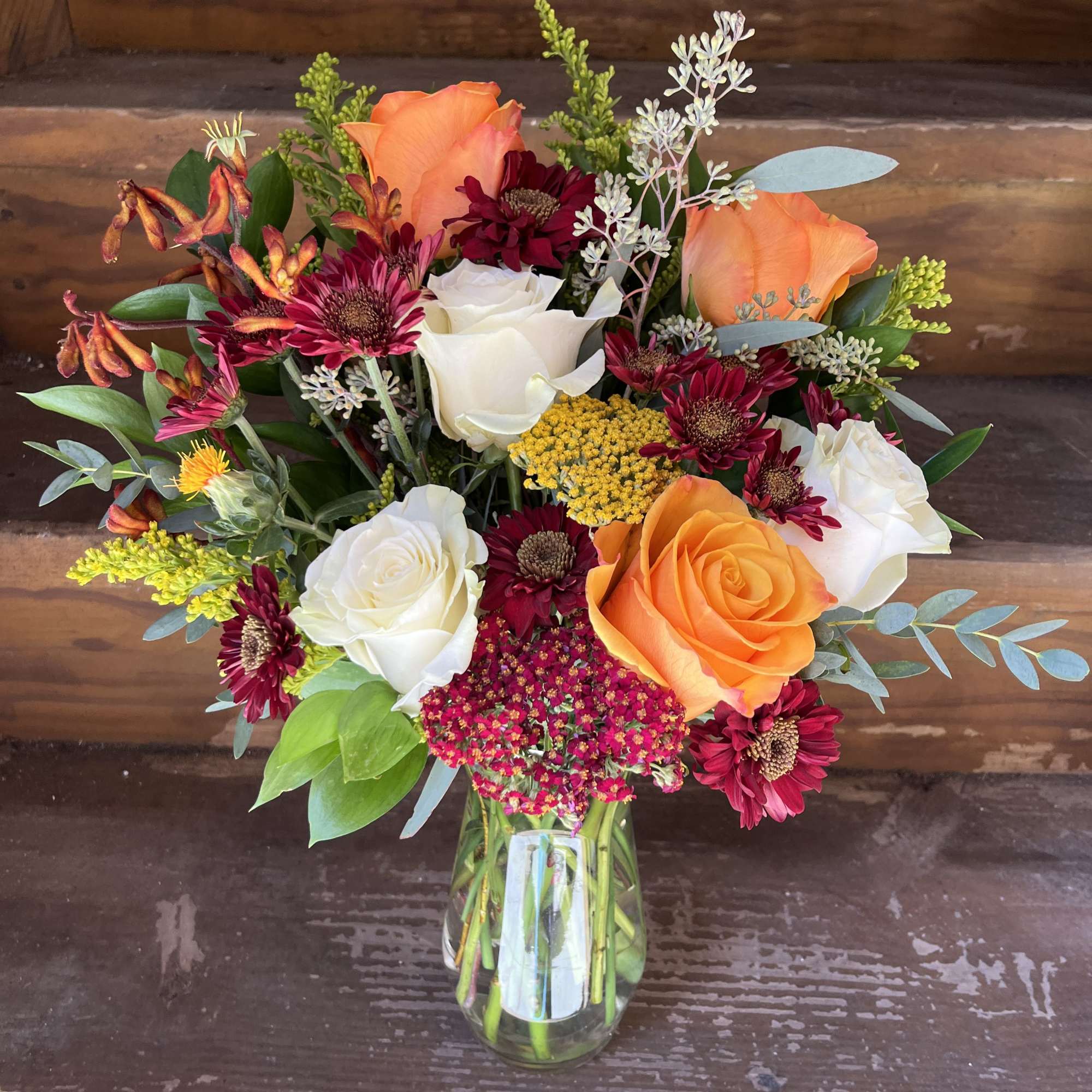 Mixed bouquet of orange and white roses in a glass vase