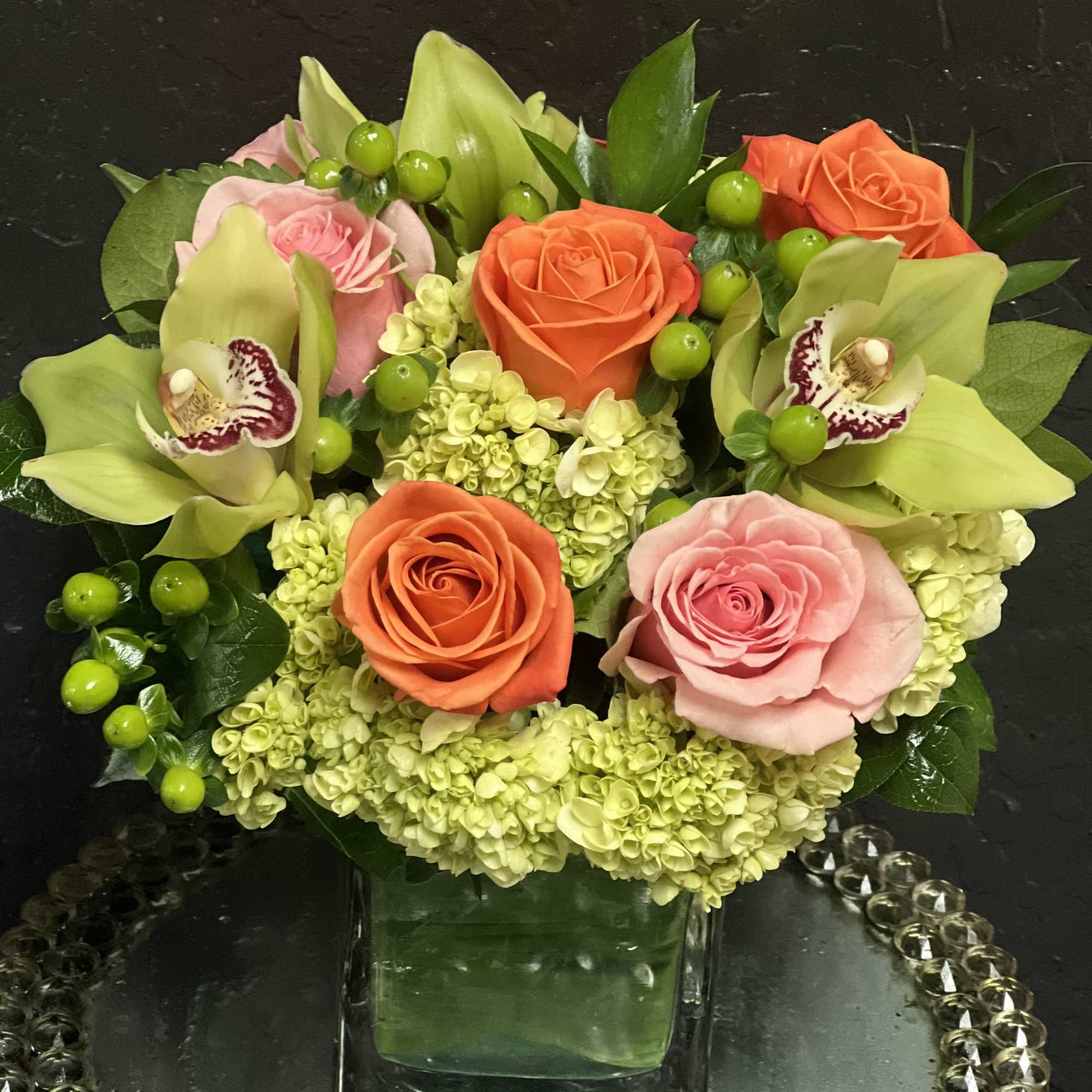 Mixed bouquet of roses, orchids, and hydrangeas in a glass vase
