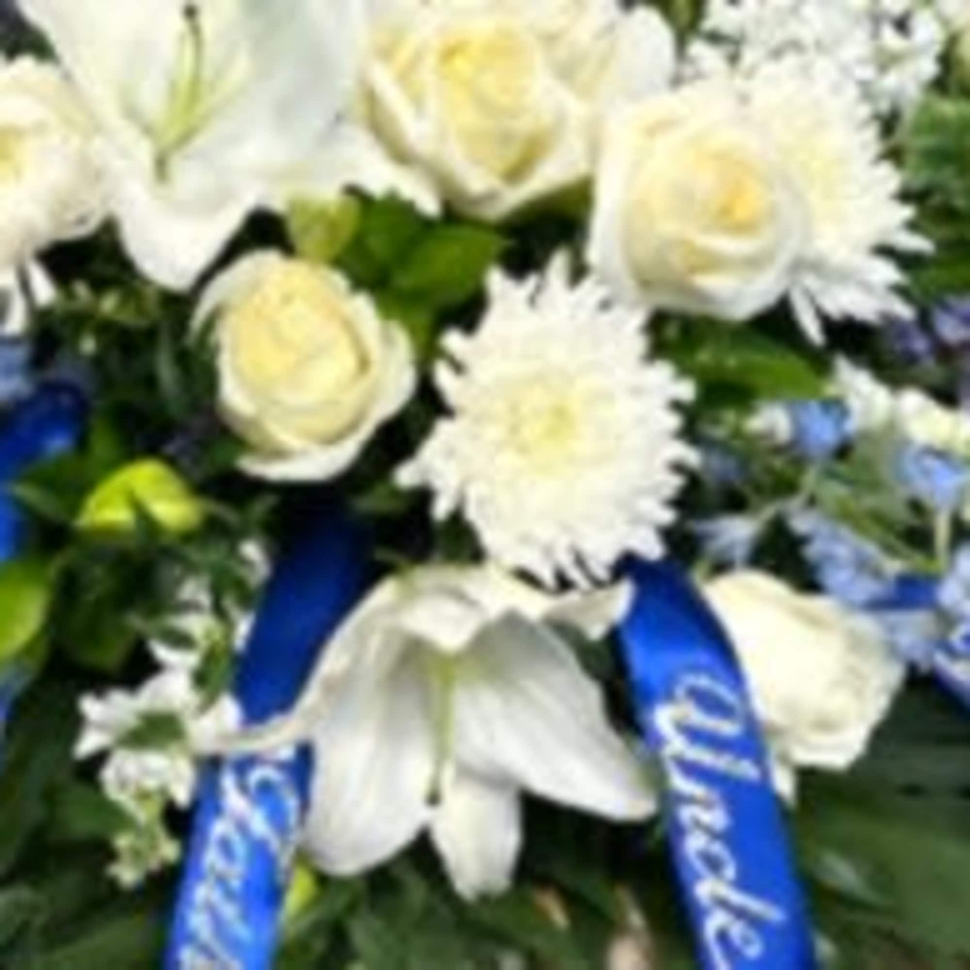White floral funeral spray with blue ribbons