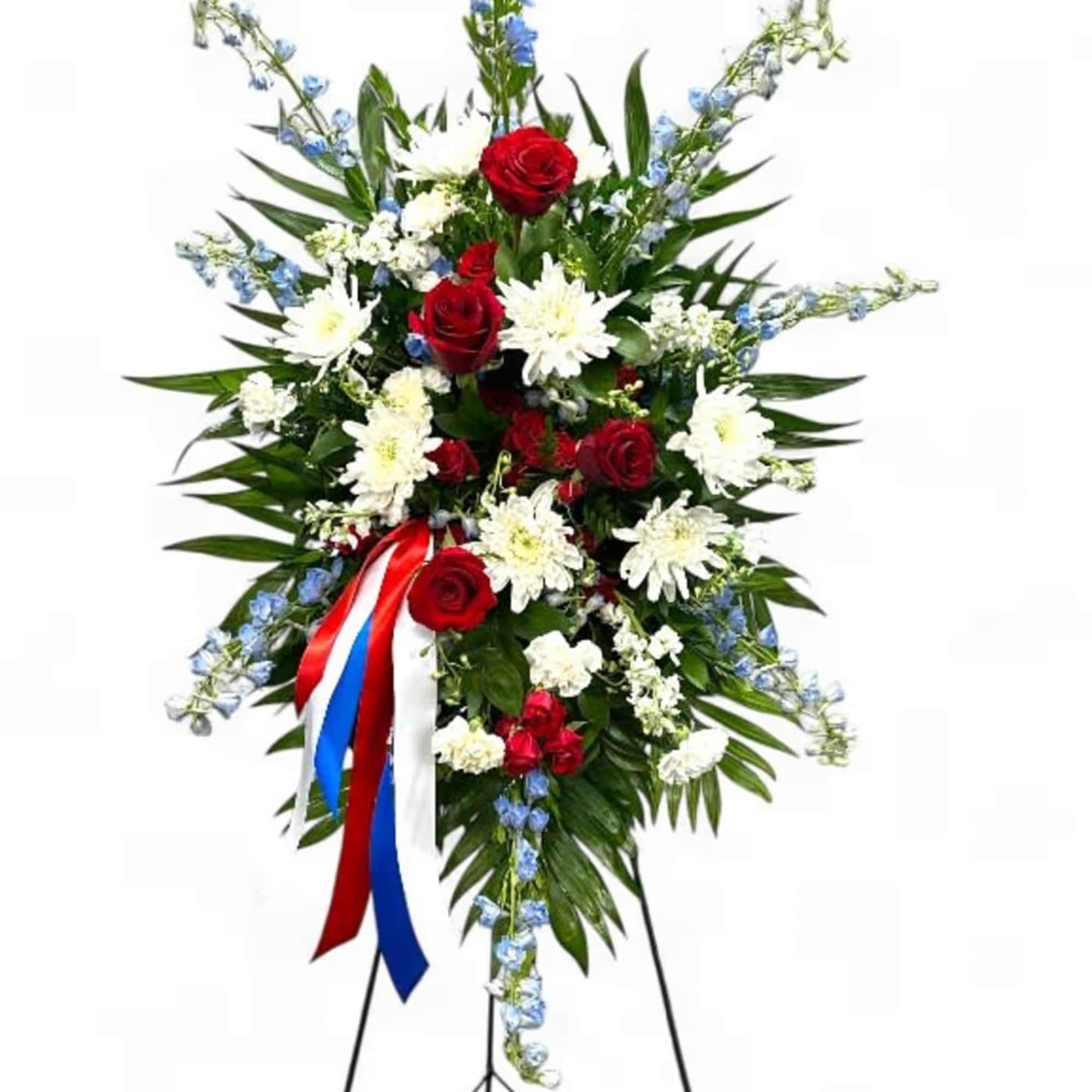 Standing floral spray with red roses, white daisies, and blue accents on an easel