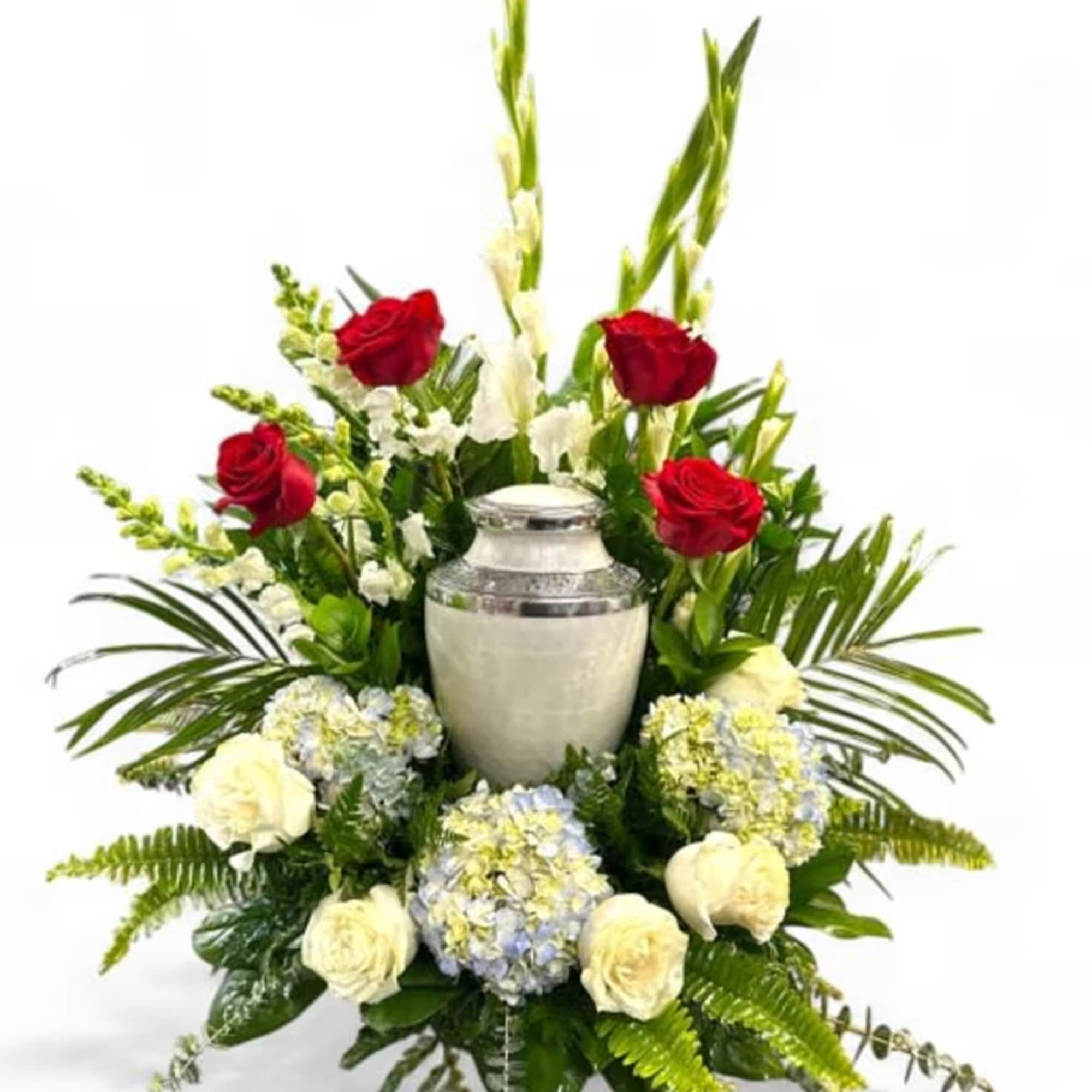 Red roses and white flowers arranged around a silver urn