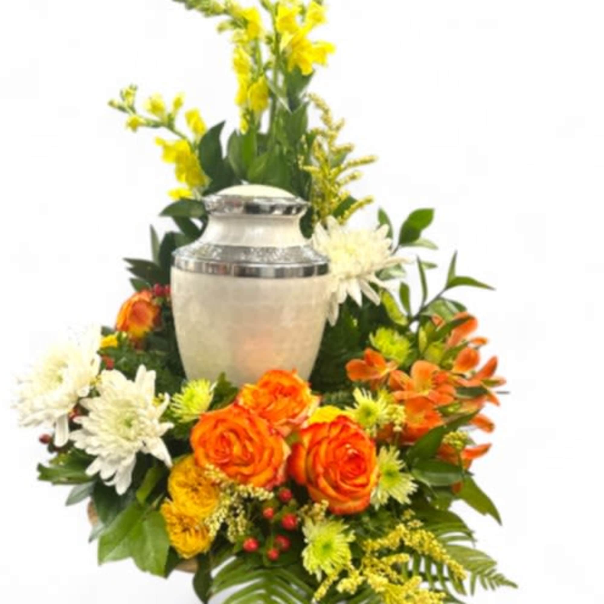Orange and white flowers arranged around a silver urn