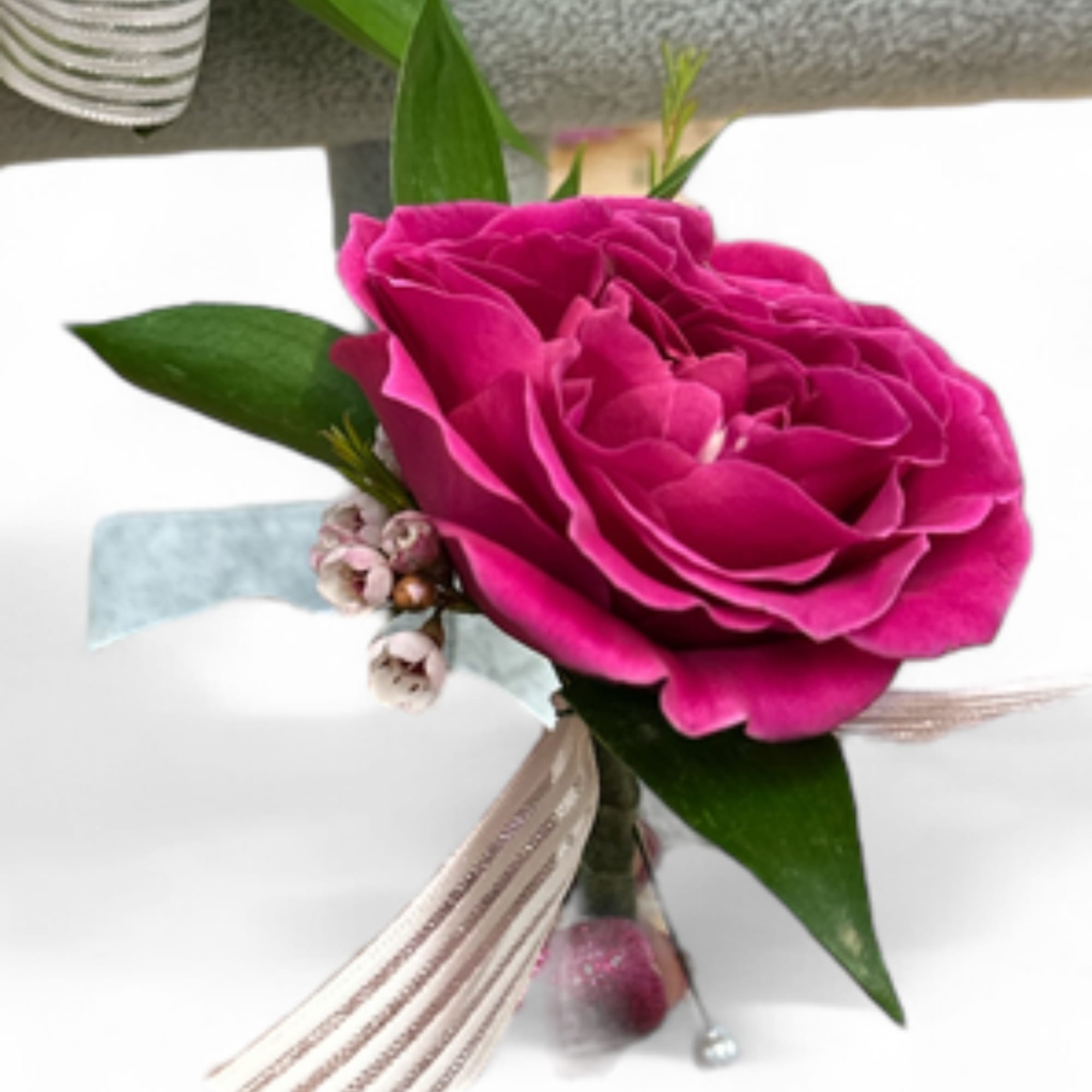 Pink rose boutonniere with ribbon and small berry accents
