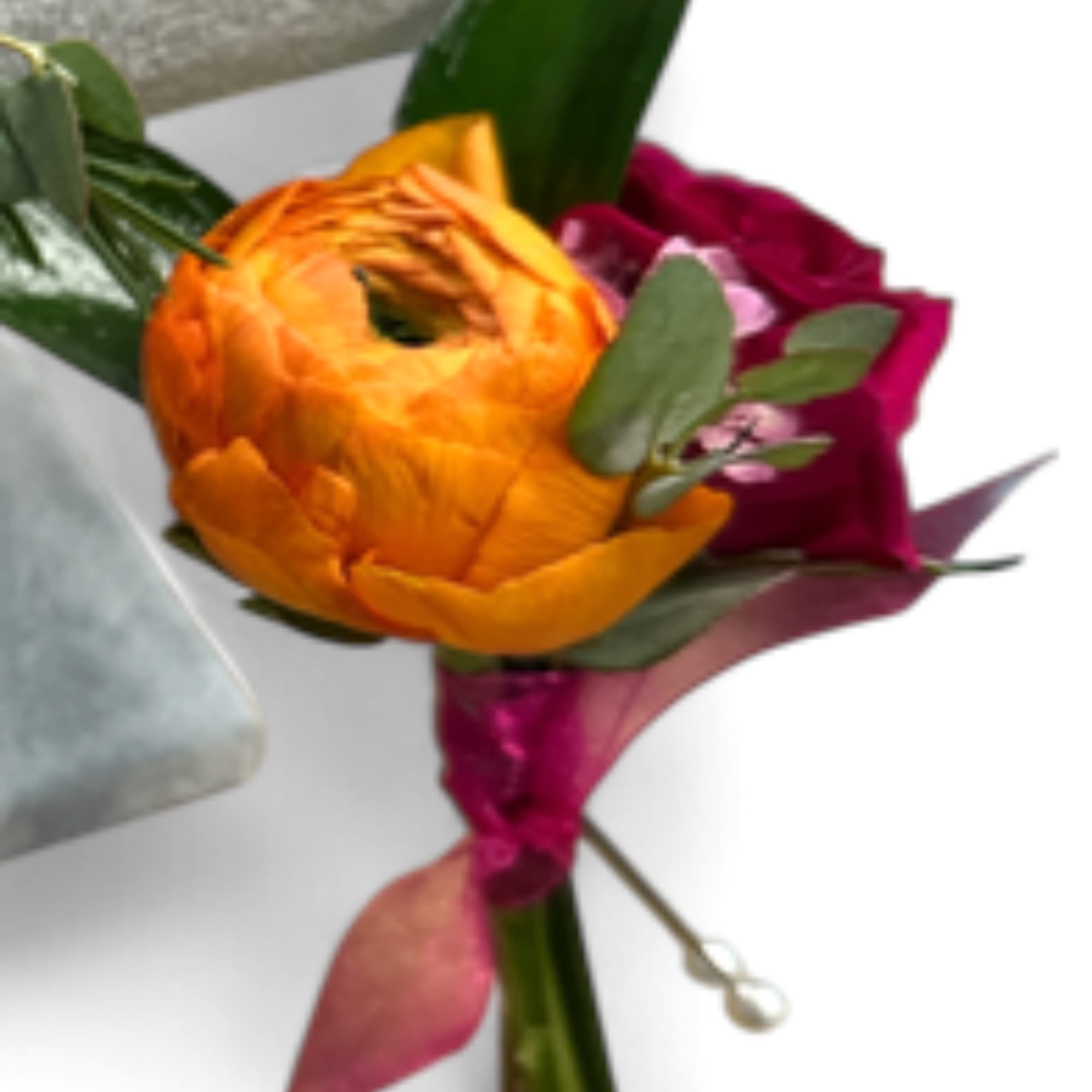 Orange and magenta ranunculus bouquet with green leaves