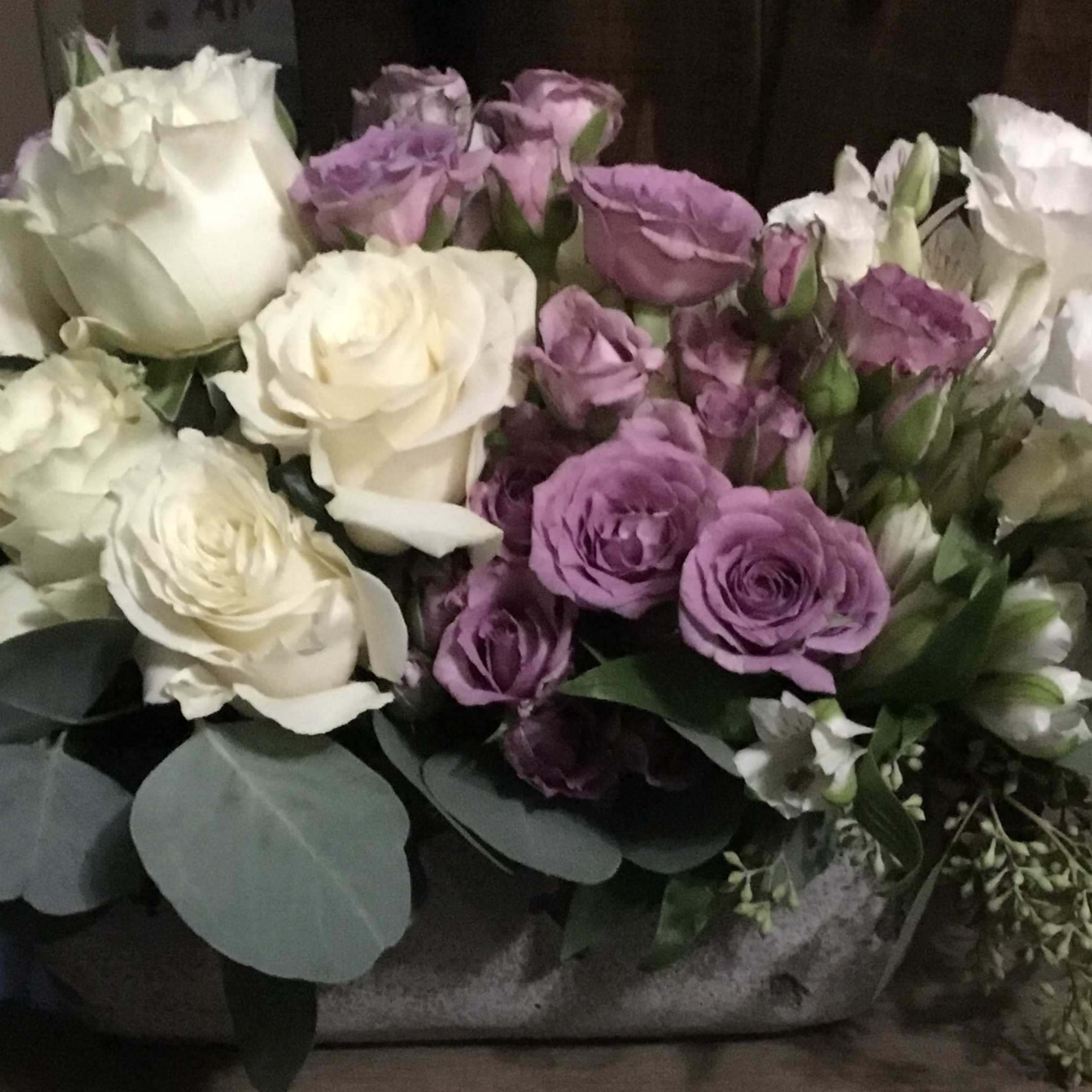 Bouquet of white and lavender roses with eucalyptus in a container