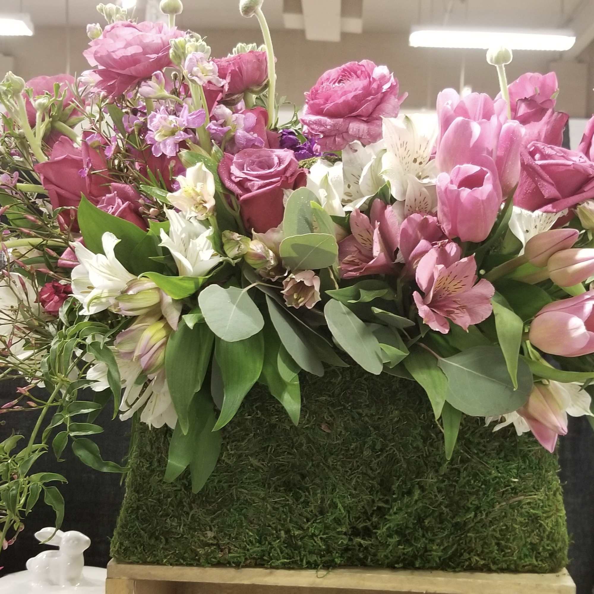 Pink and white mixed flower arrangement in a moss-covered container