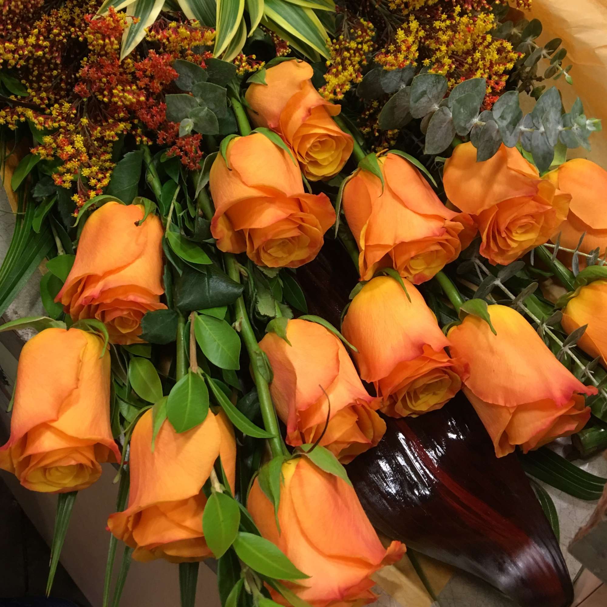 Bouquet of orange roses with mixed greenery and small filler flowers