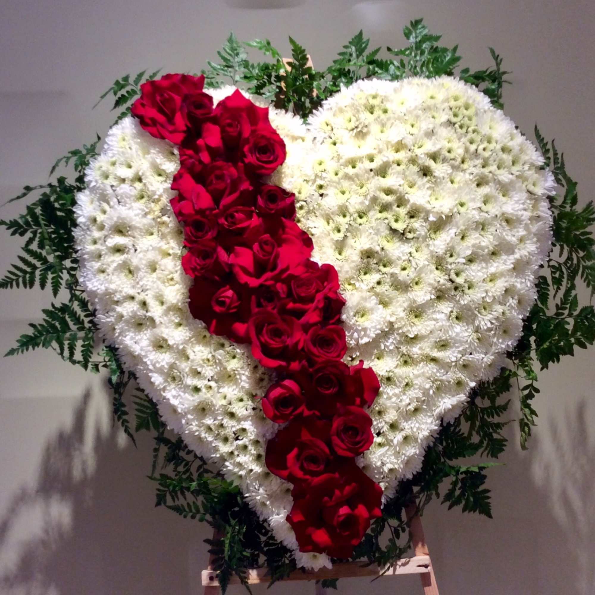 Heart-shaped floral spray with white flowers and a red rose stripe