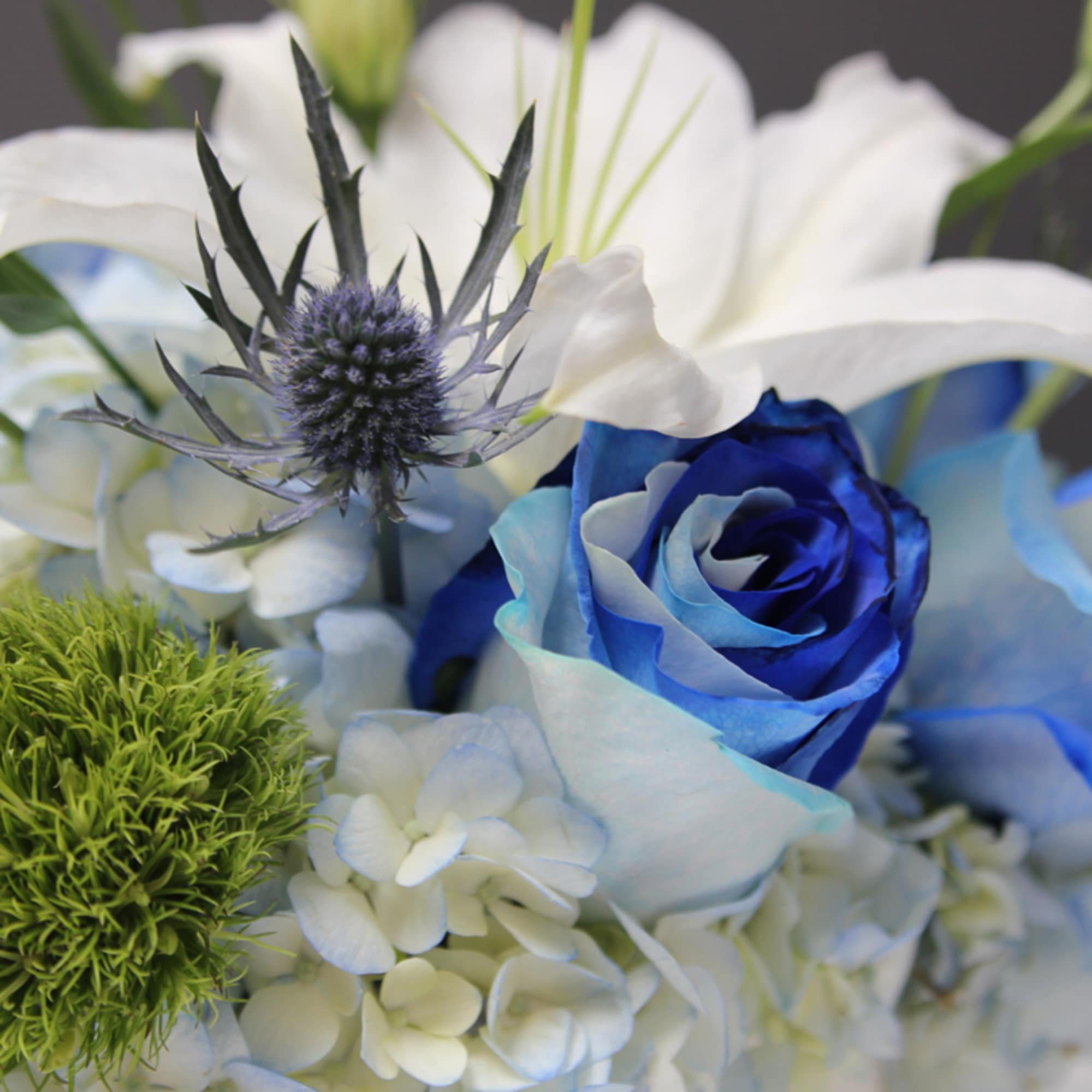 Blue rose with white lilies and spiky thistle-like bloom