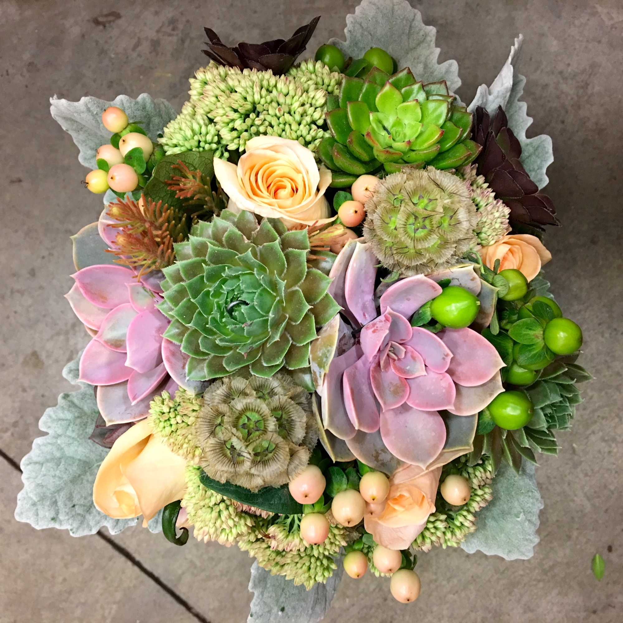Succulent bouquet with peach roses and pale berries