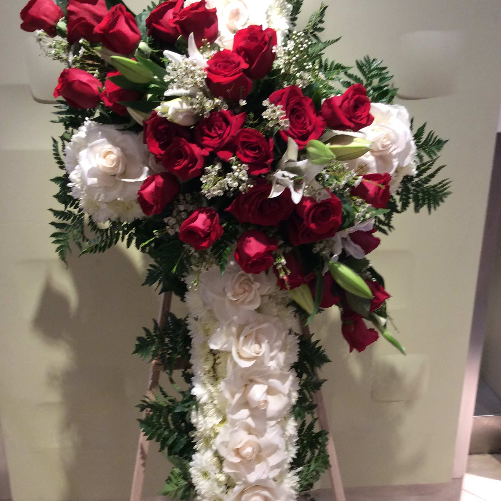 Standing floral cross with red and white roses on an easel