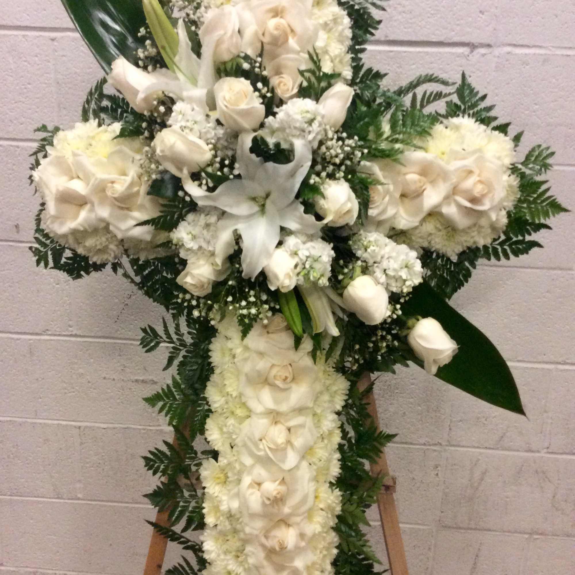 White floral cross arrangement on an easel with roses and lilies, photo 4 of 4