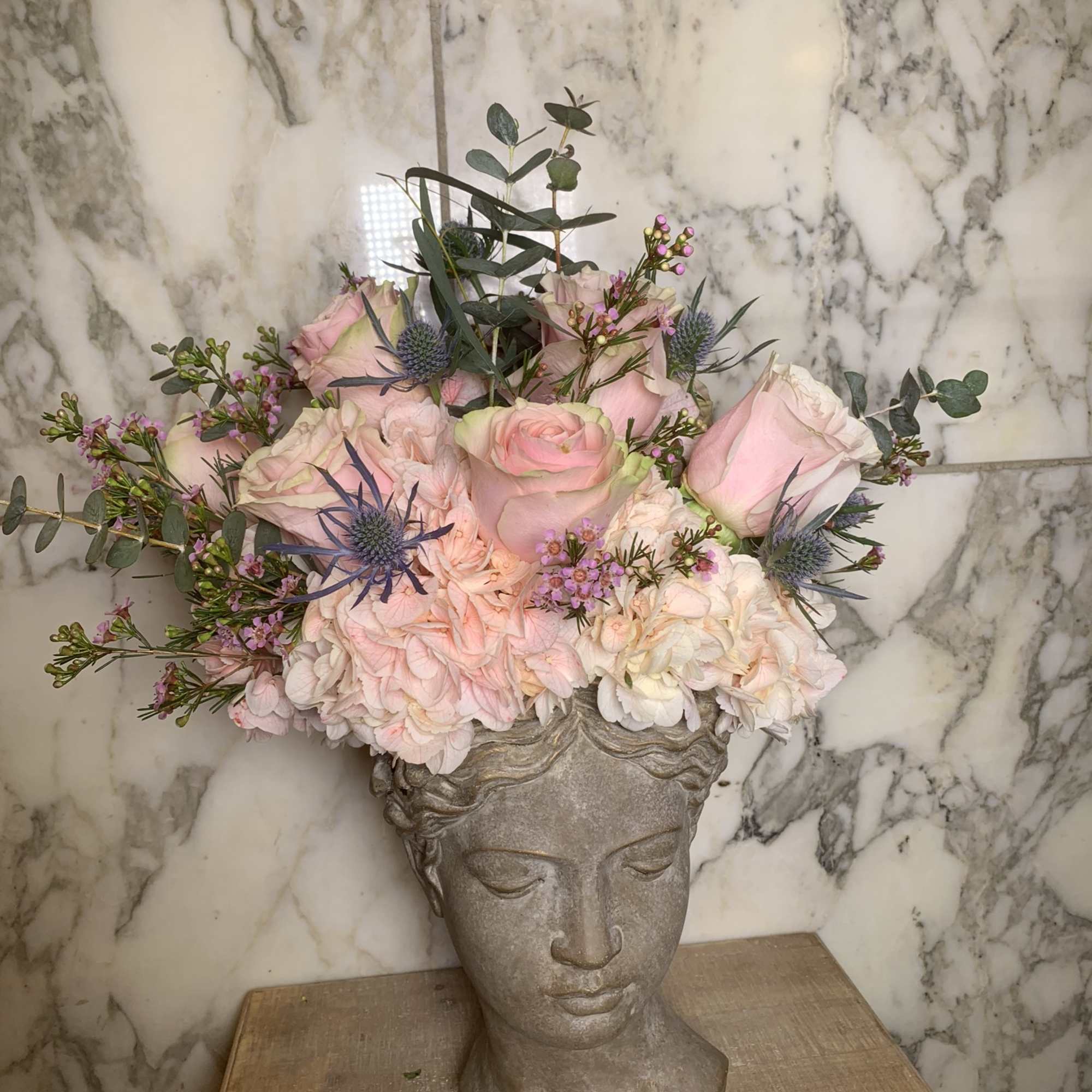 Pink rose arrangement in a sculpted bust vase