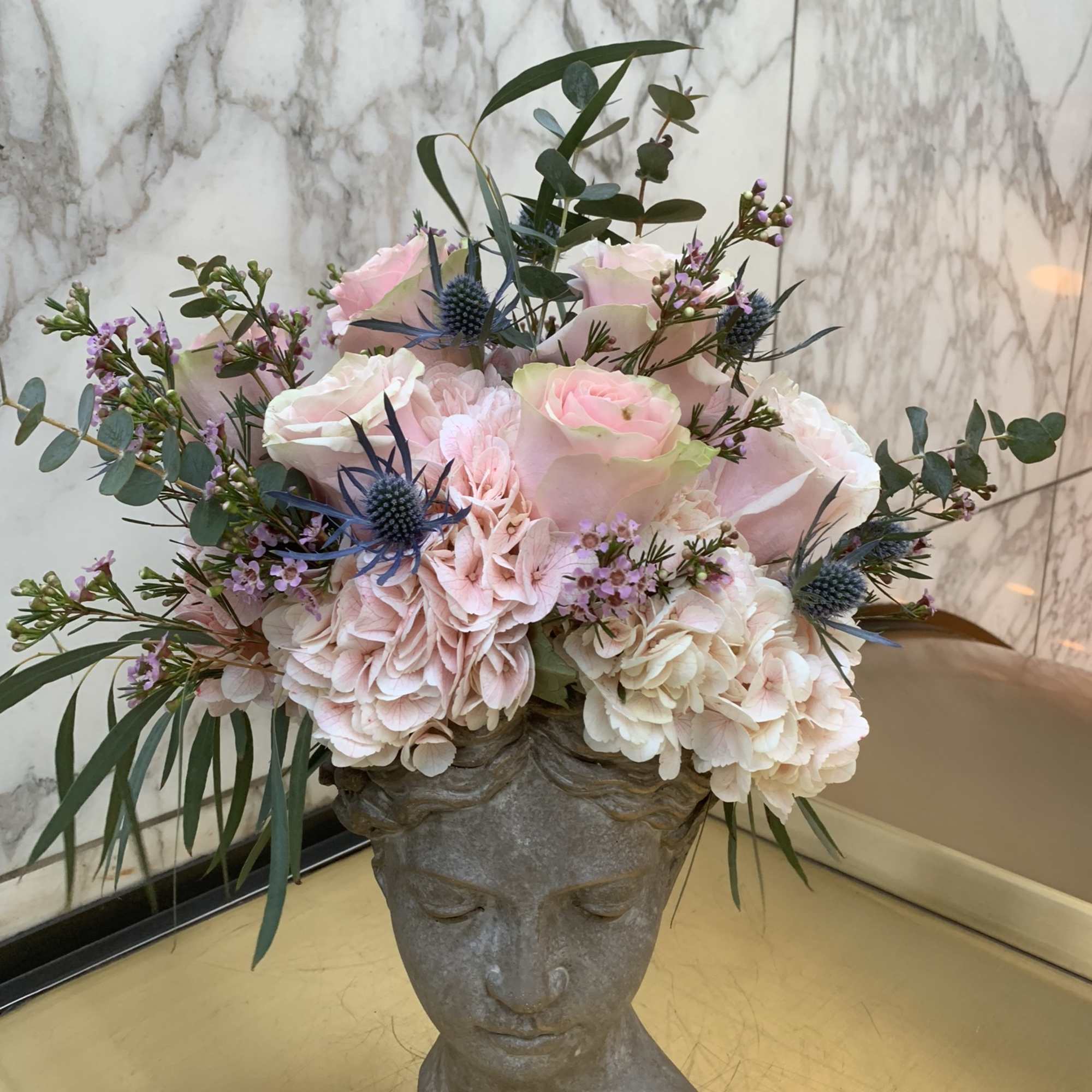 Pink and white floral arrangement in a sculpted face vase