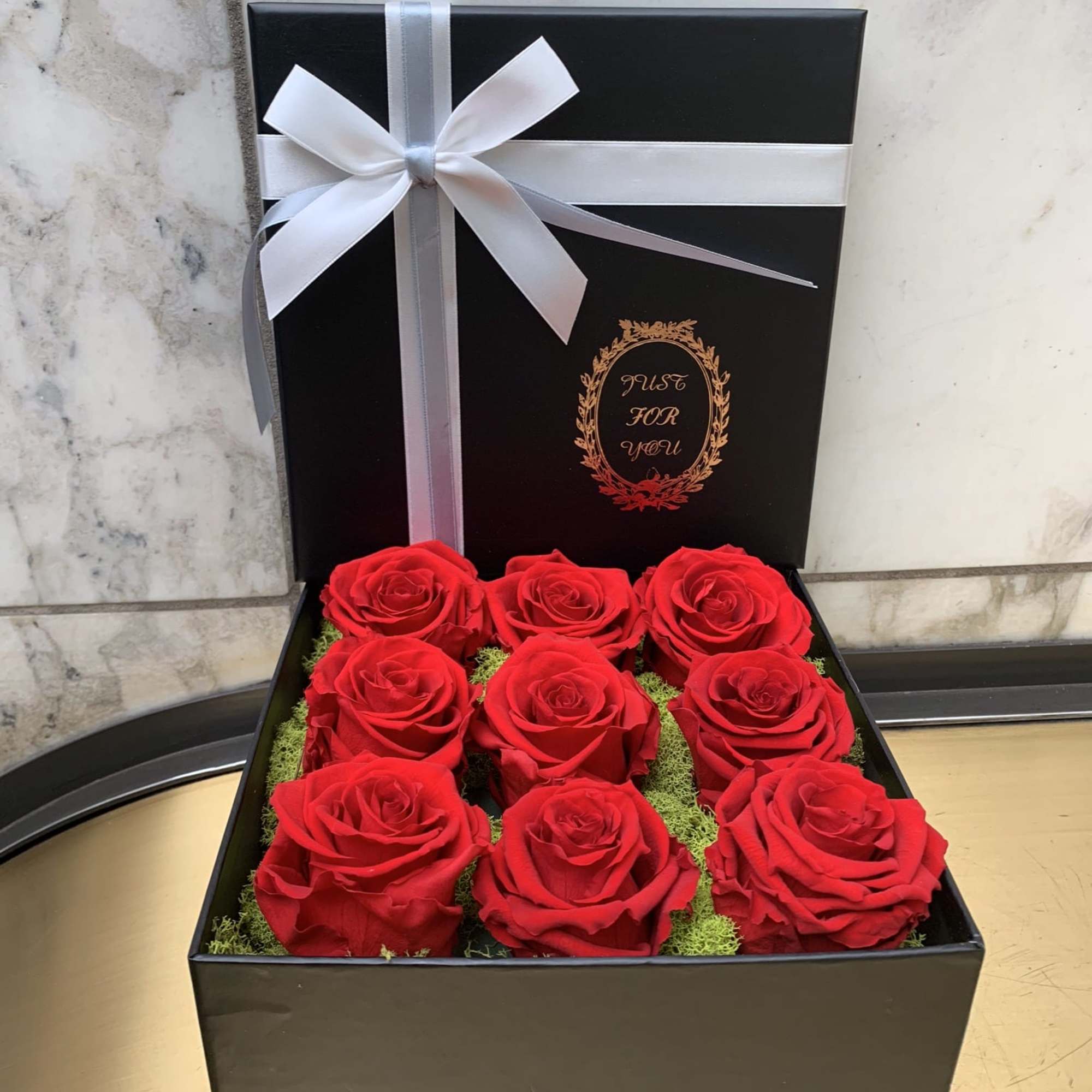Box of red roses with a white ribbon bow