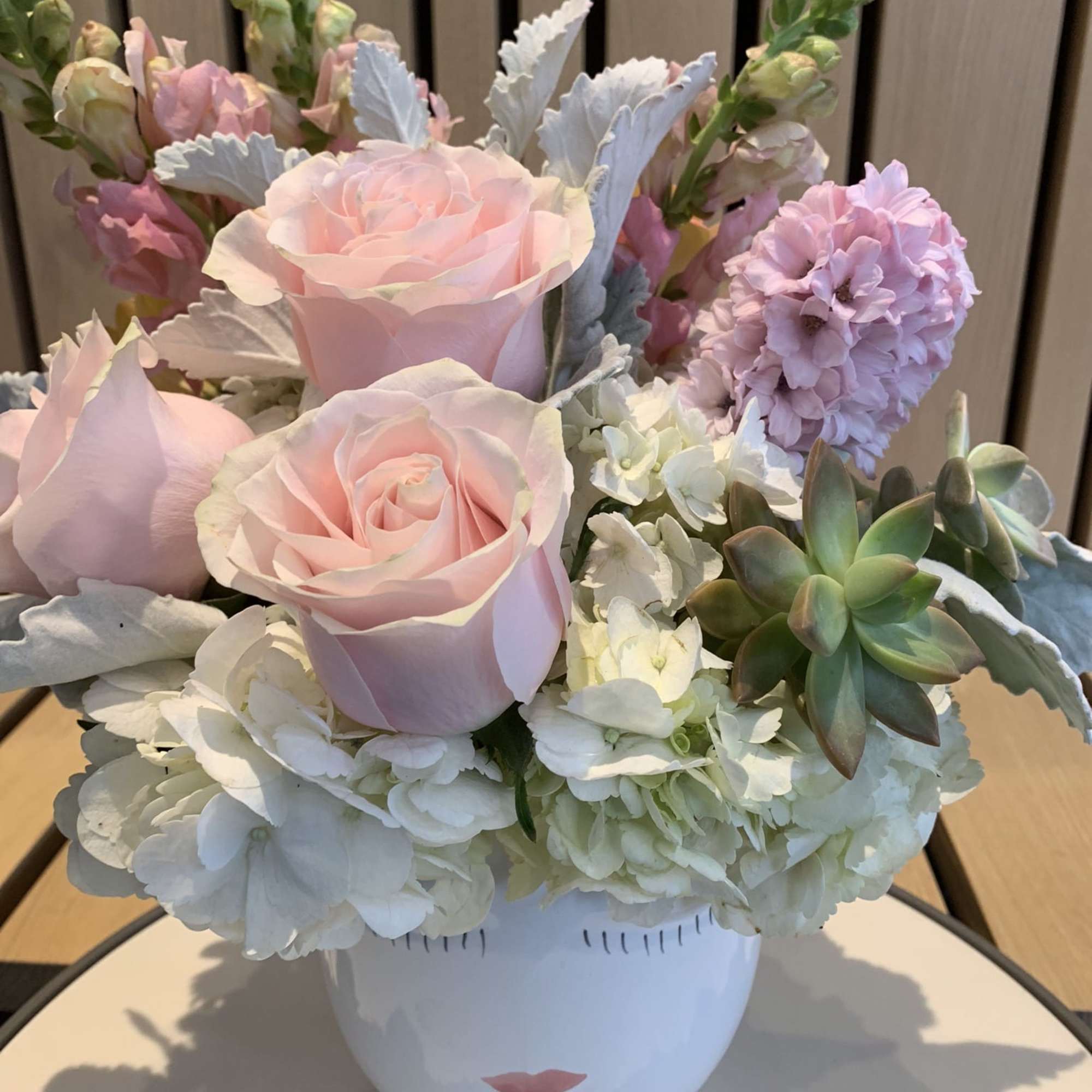 Pink roses and pastel flowers arranged in a white face vase