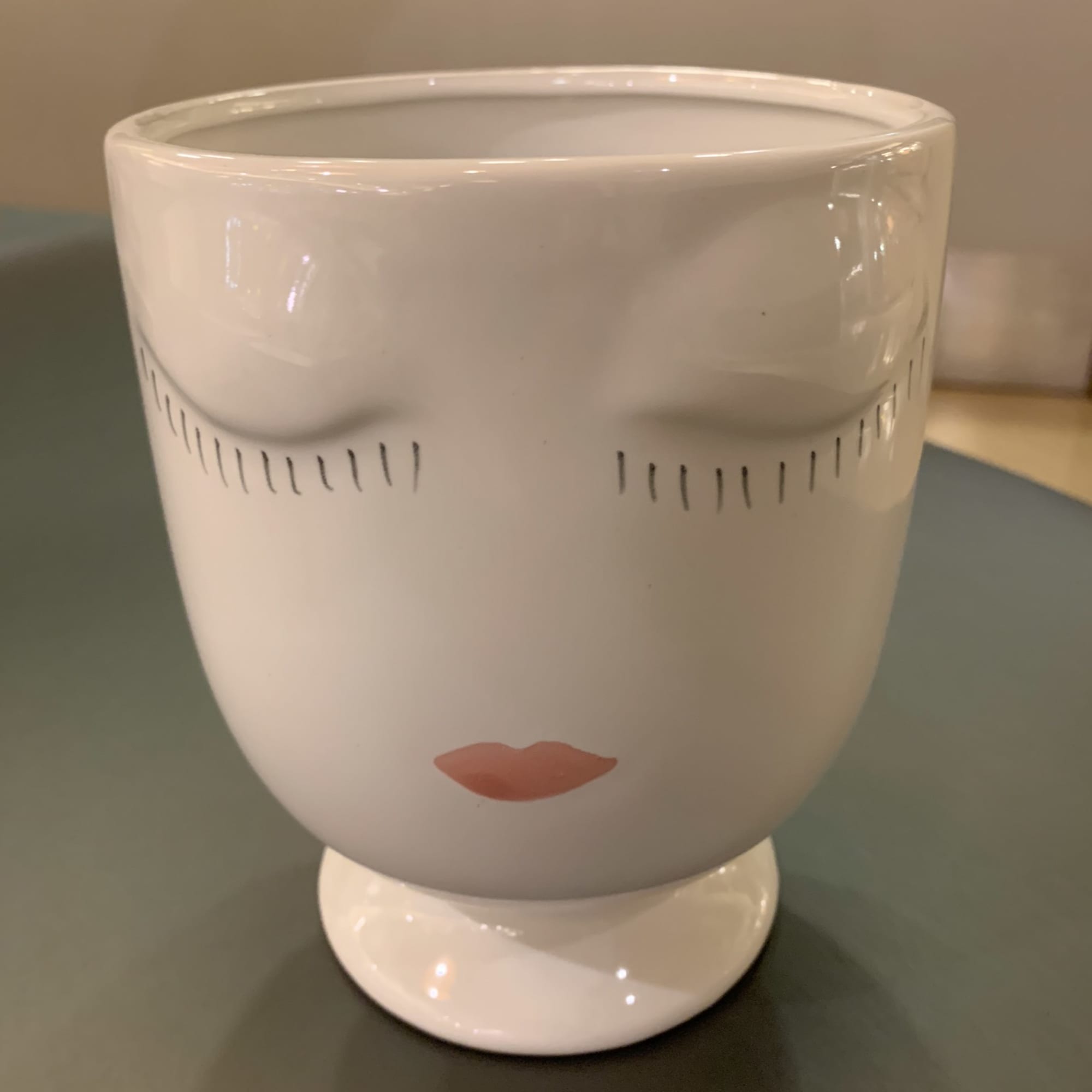 White ceramic planter with a stylized face design