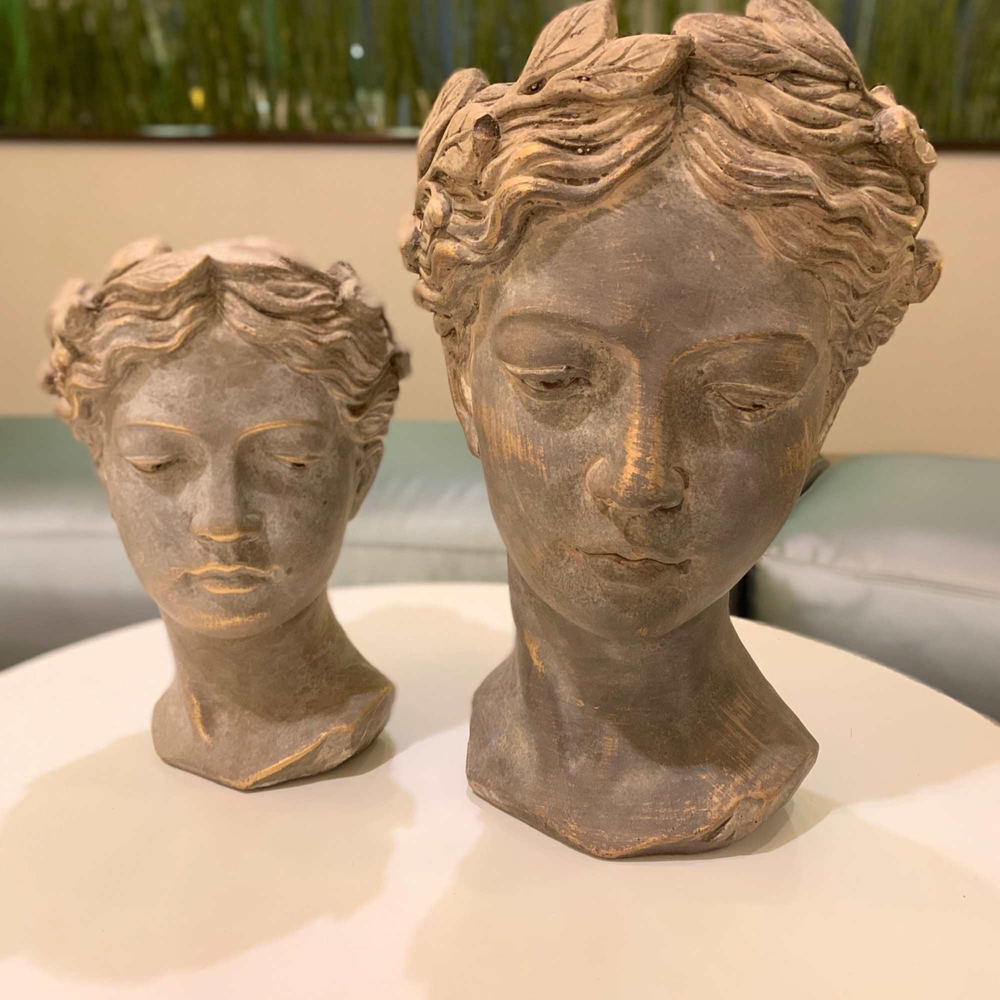 Two decorative sculpted bust planters on a round table