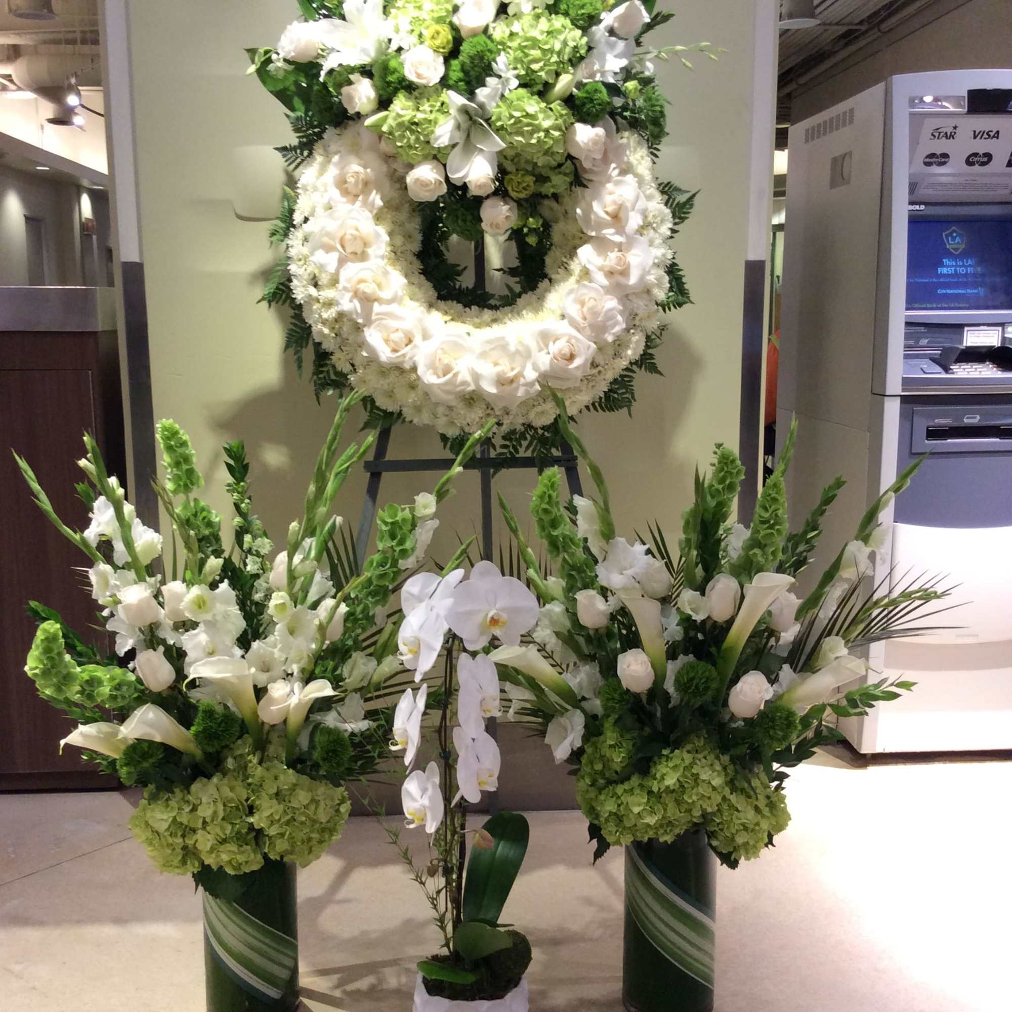 Large white and green funeral floral display with wreaths and standing arrangements