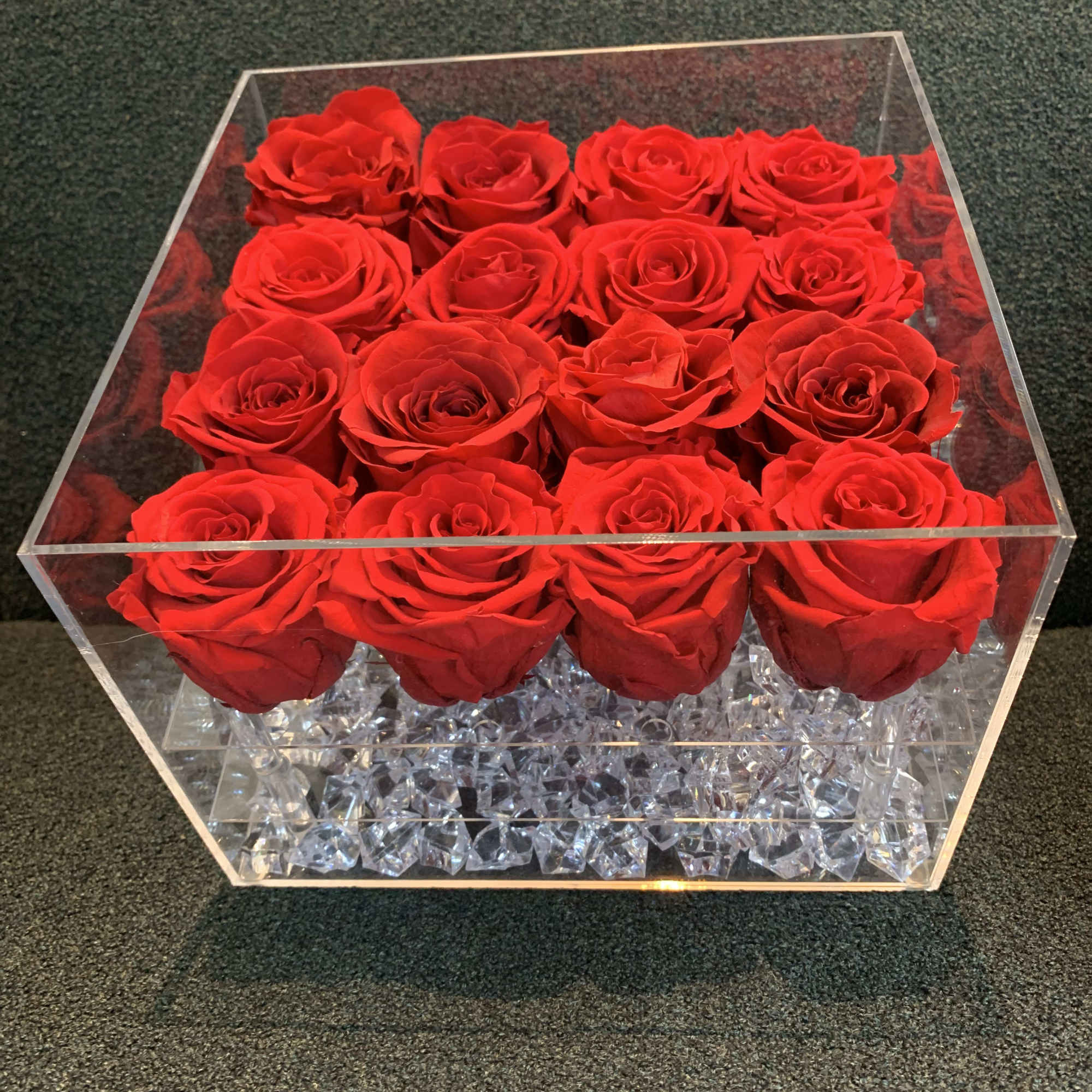 Red roses arranged in a clear square acrylic box
