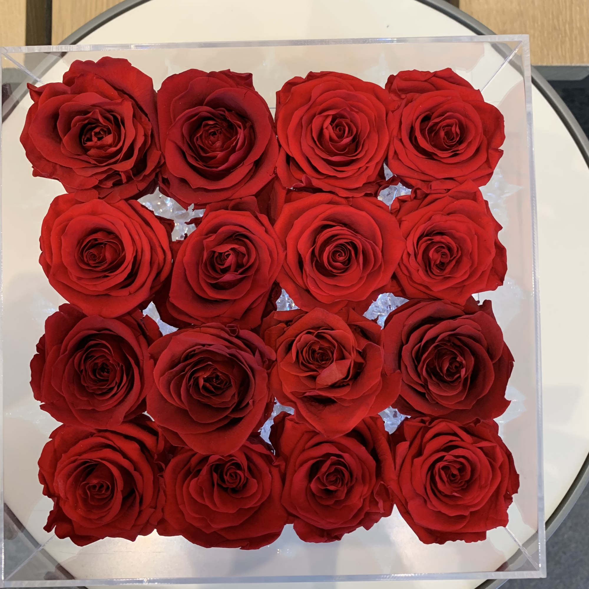 Box of red roses arranged in a square clear container
