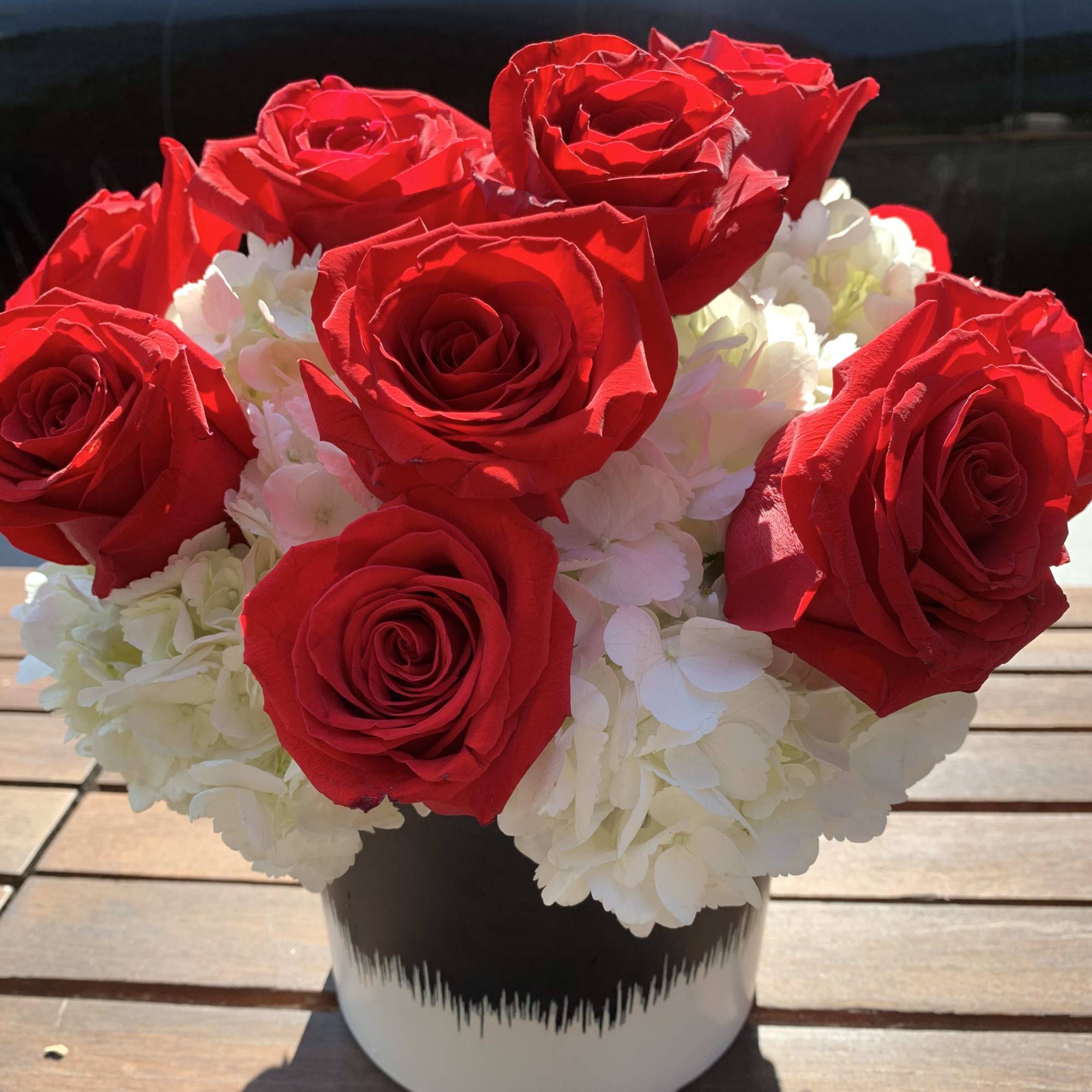 Red roses and white hydrangeas in a black-and-white vase