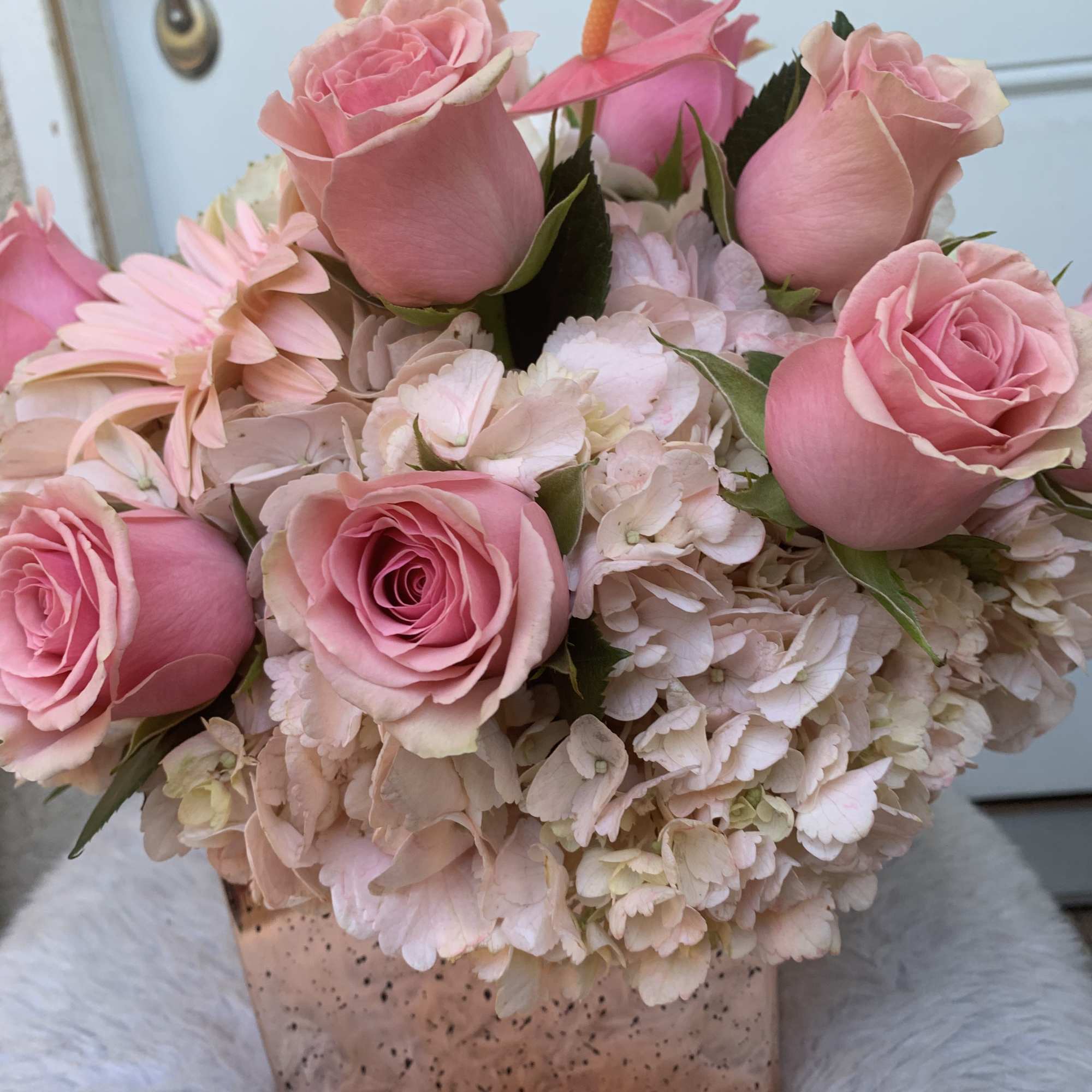 Pink roses and pale hydrangeas in a square vase