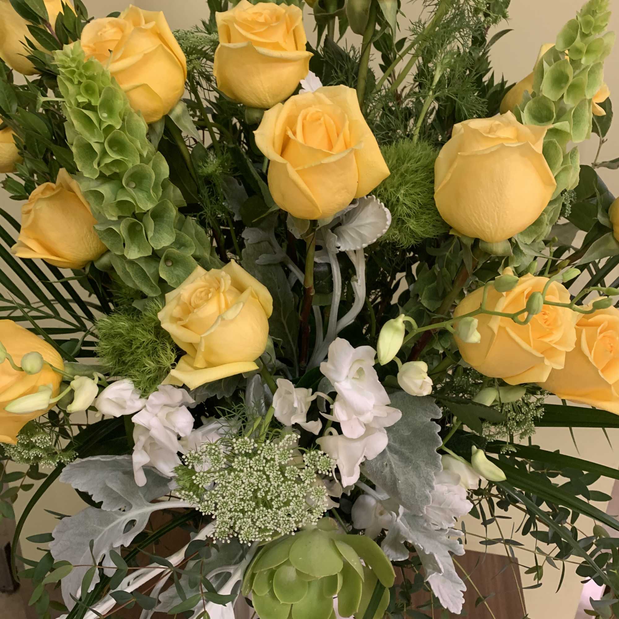 Bouquet of yellow roses with white accent flowers and greenery