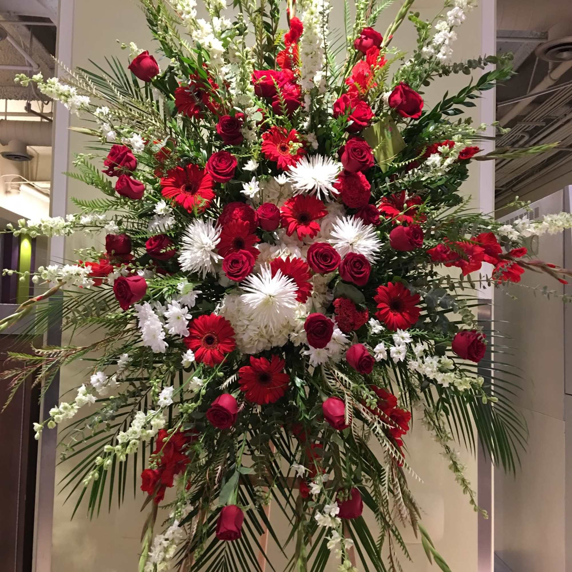 Large standing floral spray with red and white flowers on an easel