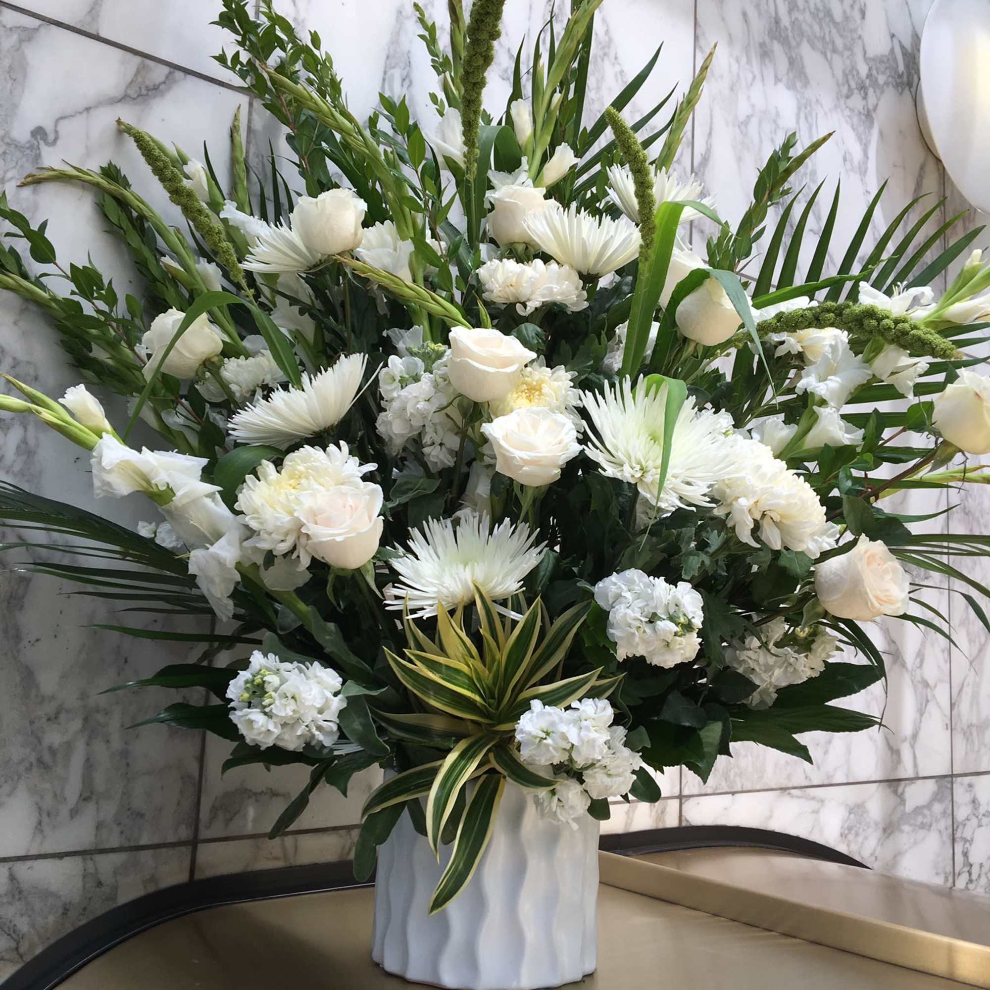 White floral arrangement in a white vase with tall greenery