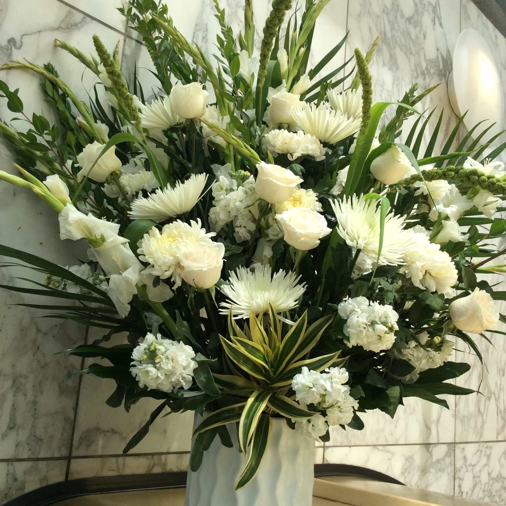 Tall white floral arrangement in a white vase with roses and chrysanthemums